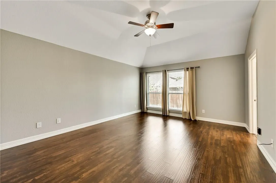 Vaulted ceiling, ceiling fan with integrated lighting, wood-finish flooring, and dual windows