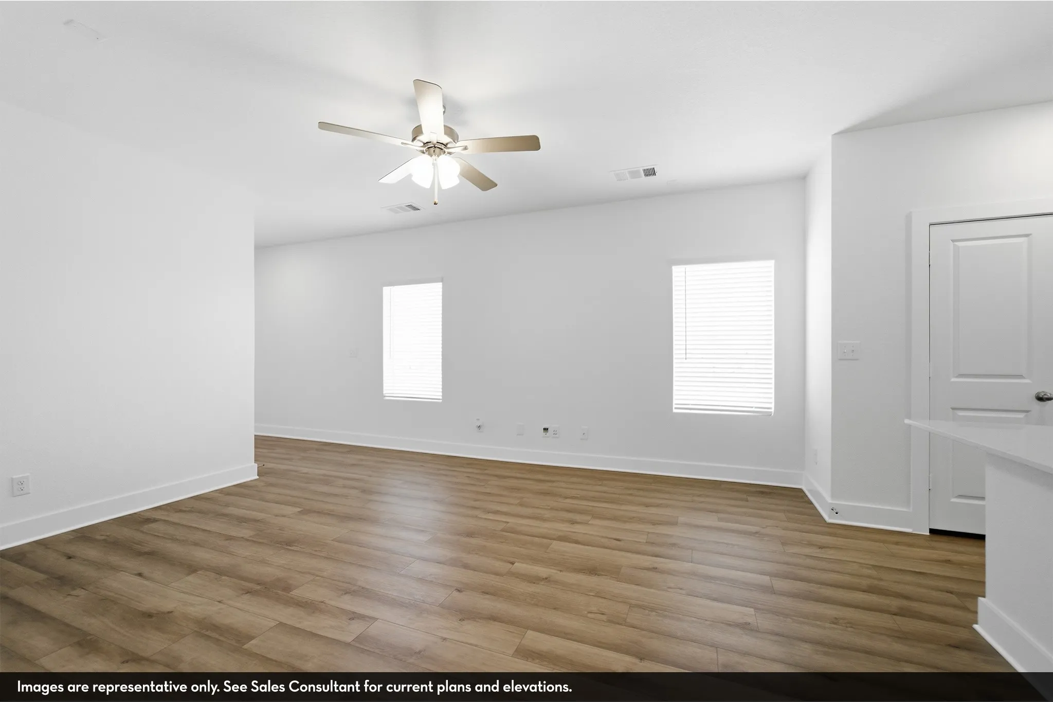 Open-concept room featuring wood-finish flooring, a ceiling fan, and two windows with blinds