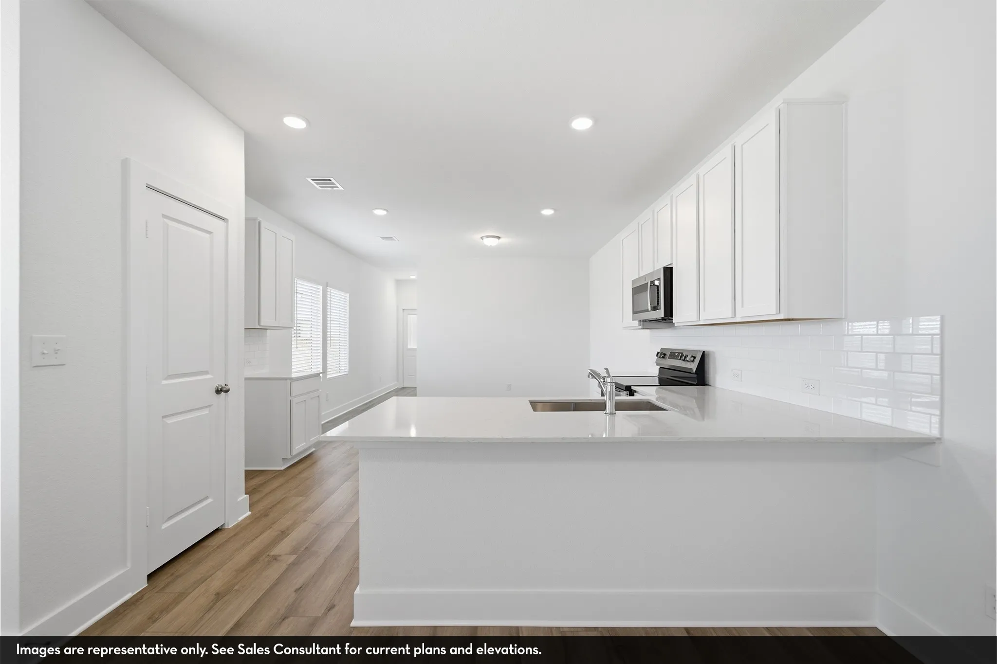 Kitchen featuring white cabinetry, subway tile backsplash, stainless steel appliances, and a peninsula with a sink