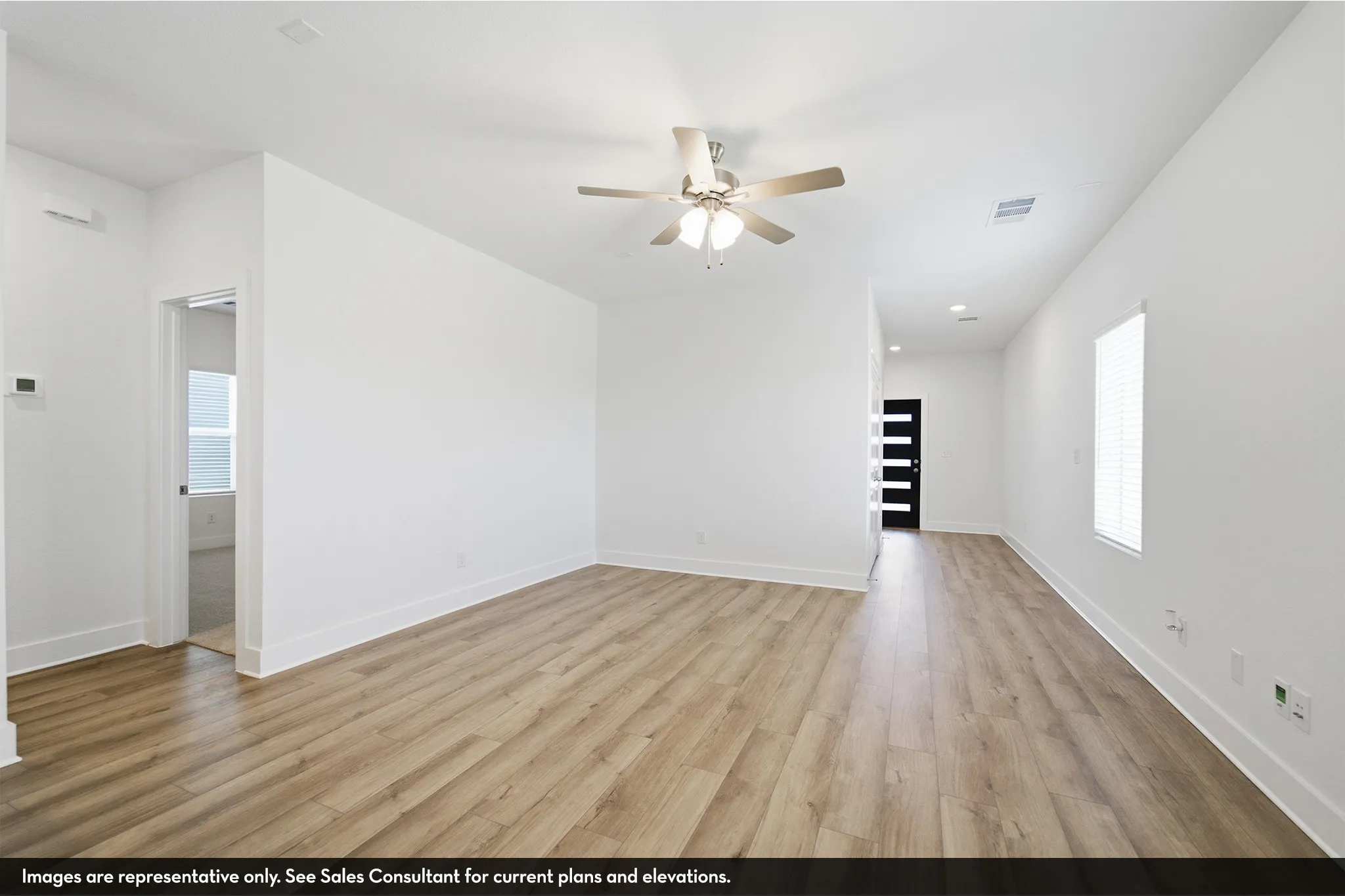 Wood-finish flooring throughout, white walls, and a ceiling fan with integrated lighting