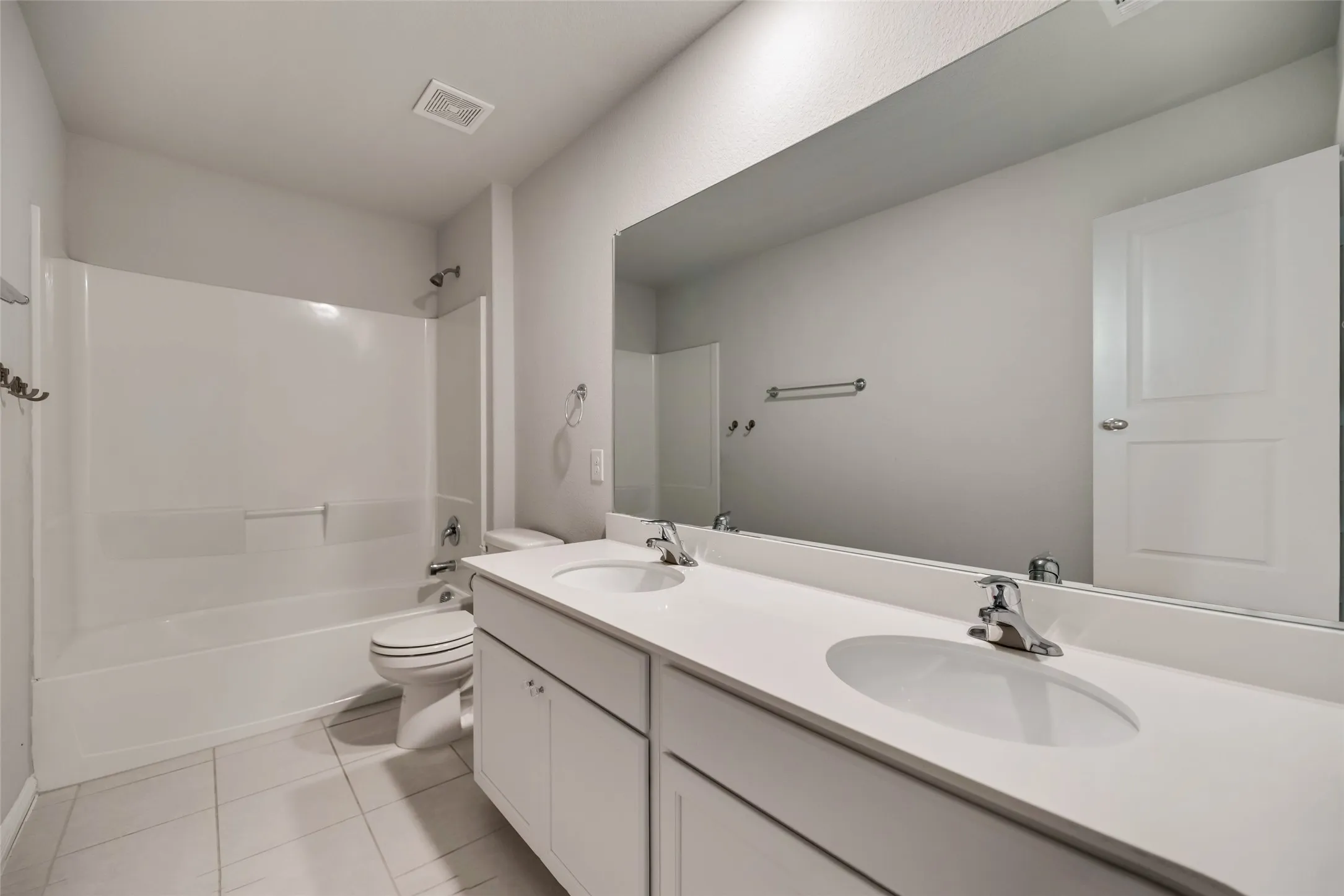 Dual vanity with integrated sinks, full-width mirror, white cabinetry, and a tub/shower combination