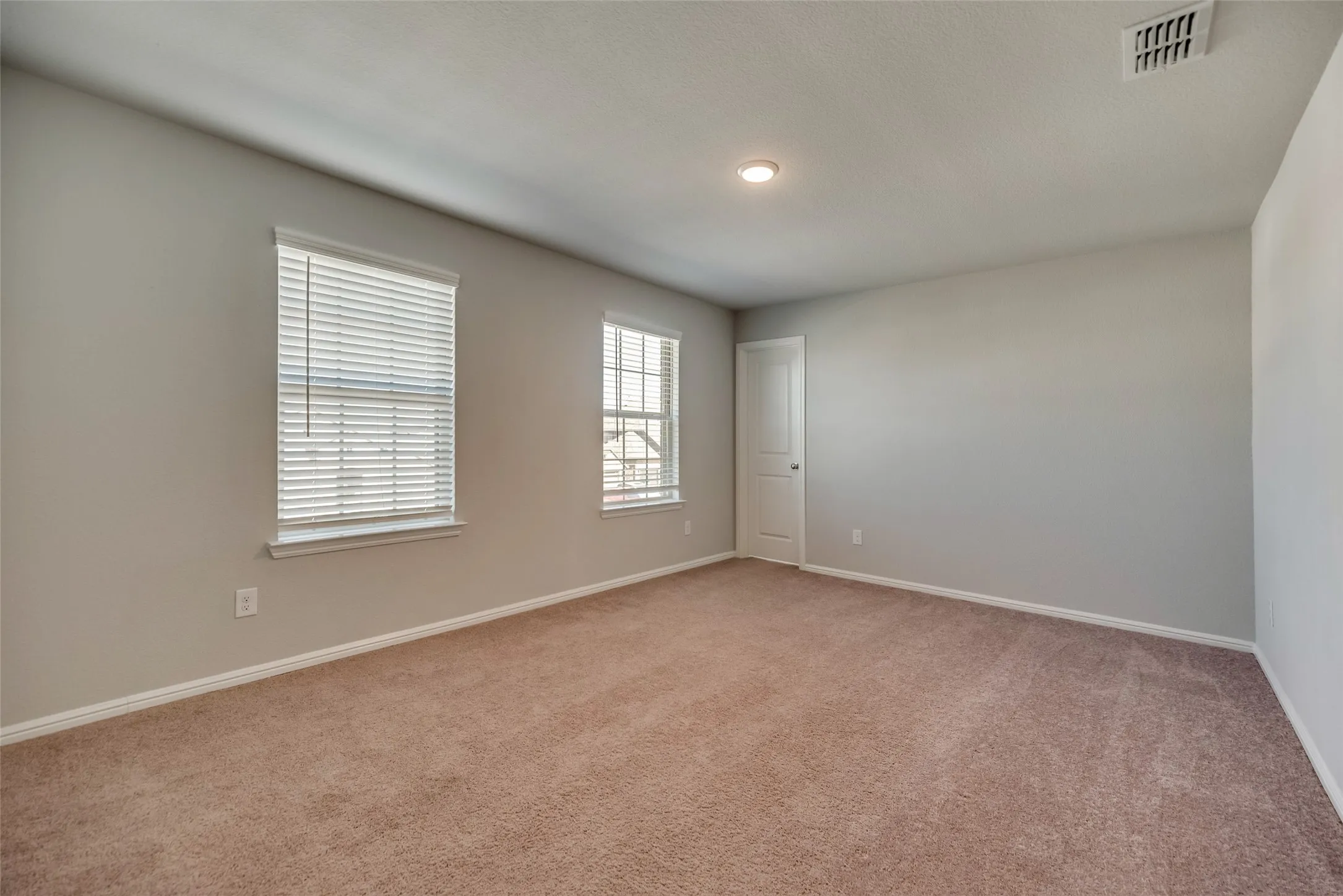 Carpeted room featuring two windows with blinds, a white door, recessed lighting, and light-toned wall paint