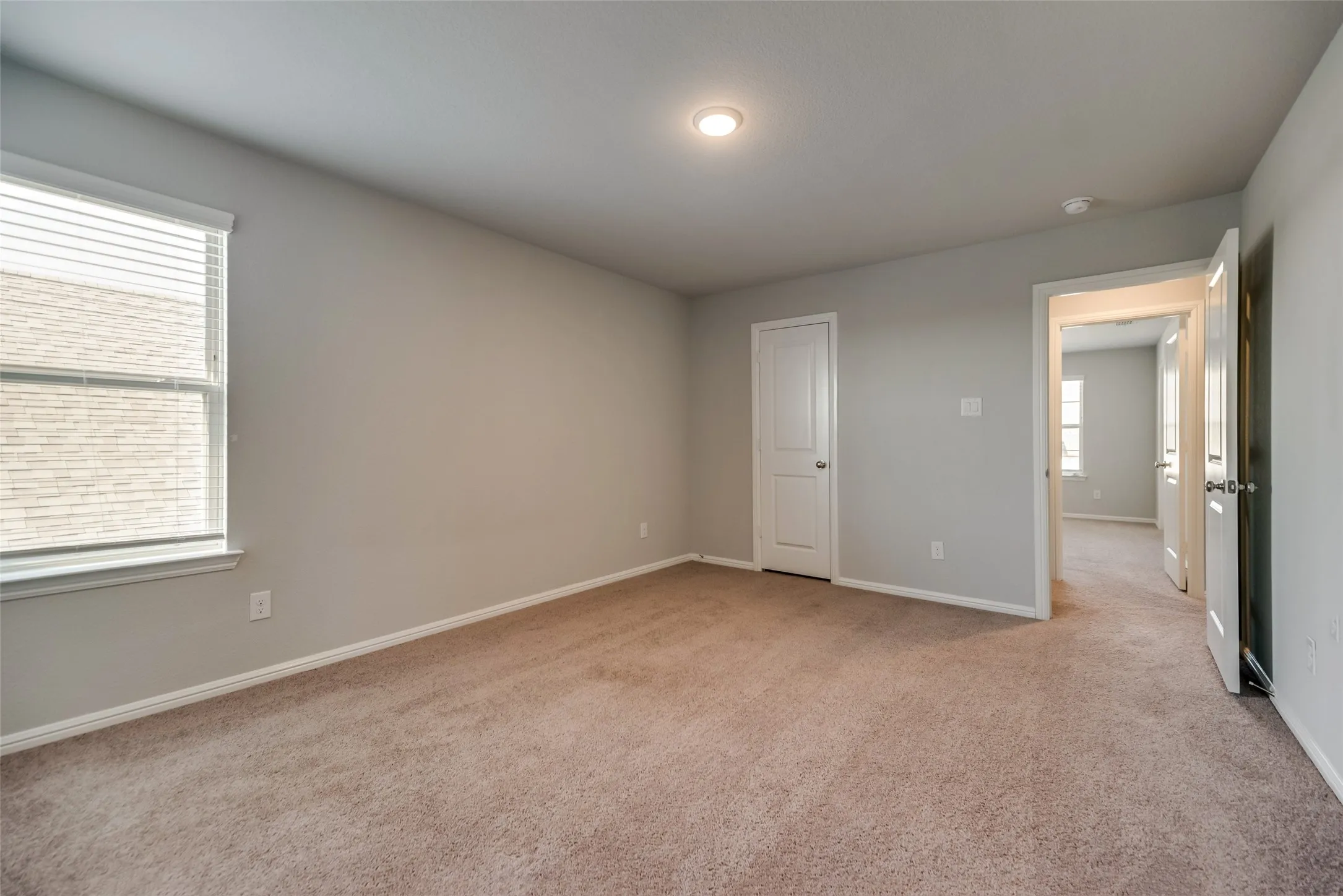 Recessed ceiling light, neutral wall color, window blinds, and light brown carpeting