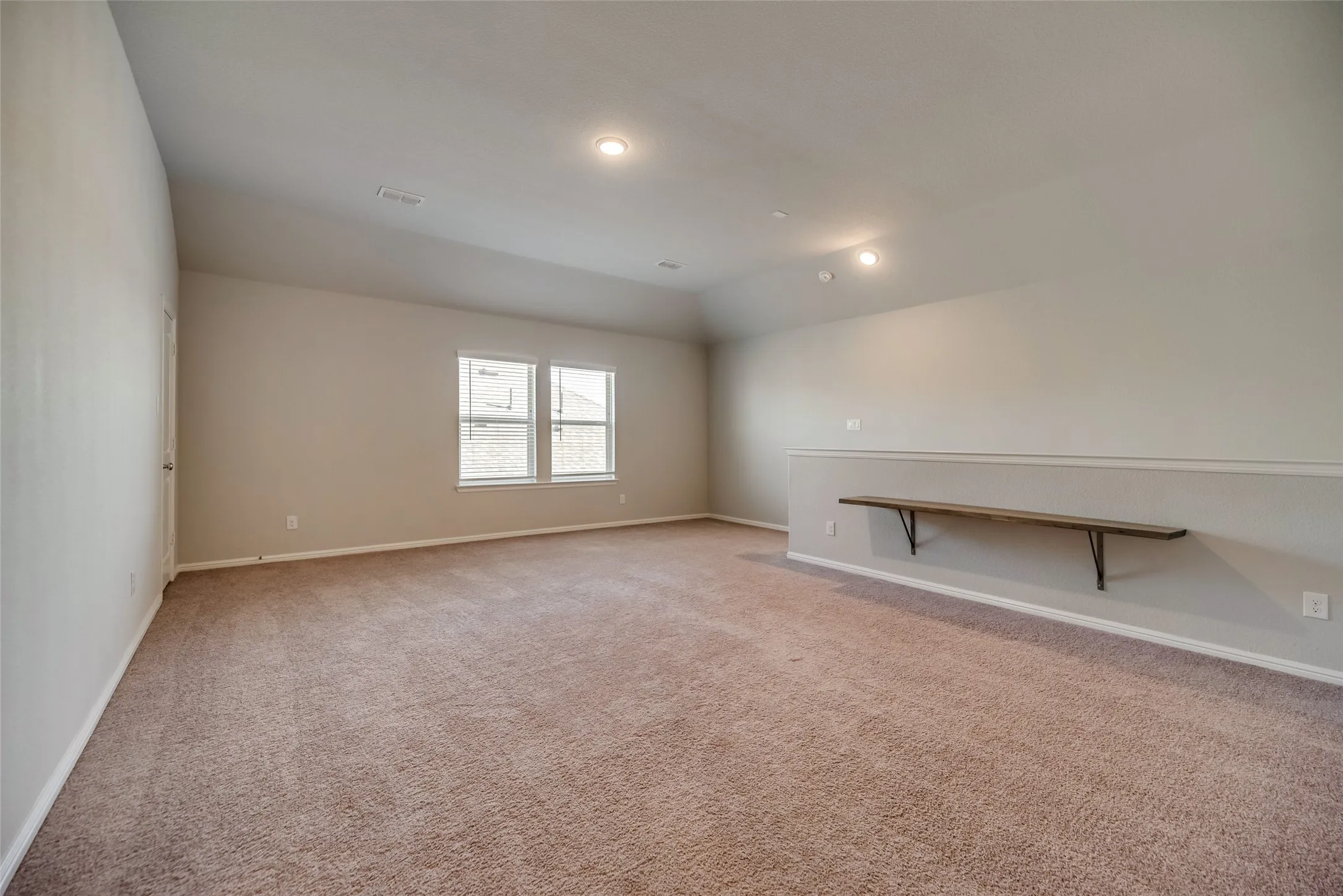 Carpeted room with recessed lighting, two windows, and a built-in wall shelf