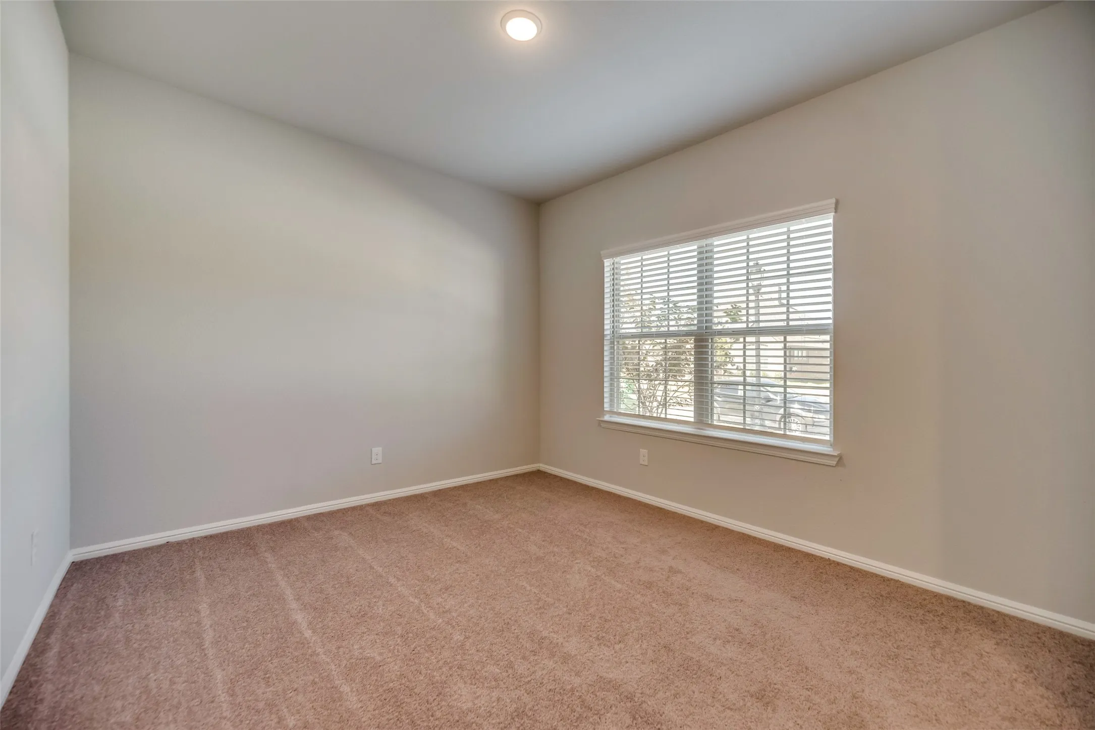 Recessed ceiling light, neutral wall tones, carpeted flooring, and window with horizontal blinds