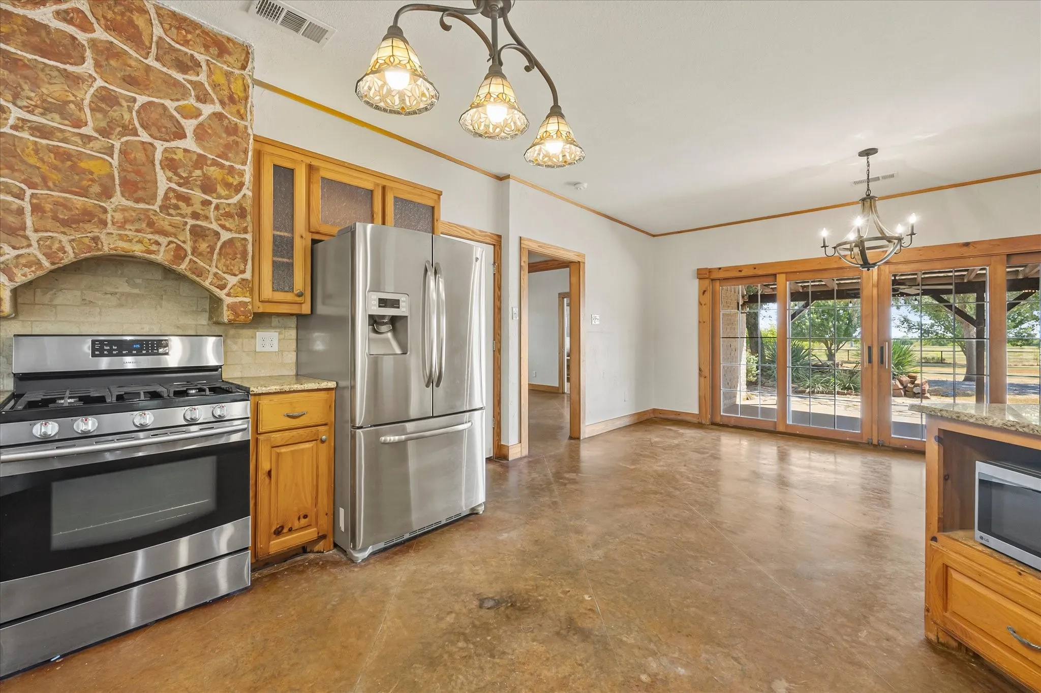 Custom stone vent a hood accents the kitchen. SS refrigerator stays.