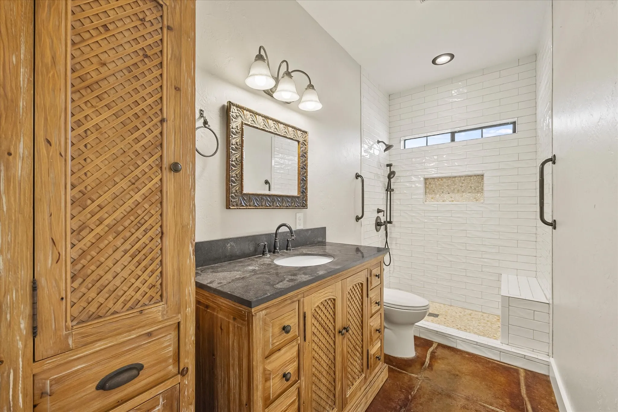 Beautifully remodeled secondary bath features new walk in shower with bench seat, granite counters, storage.