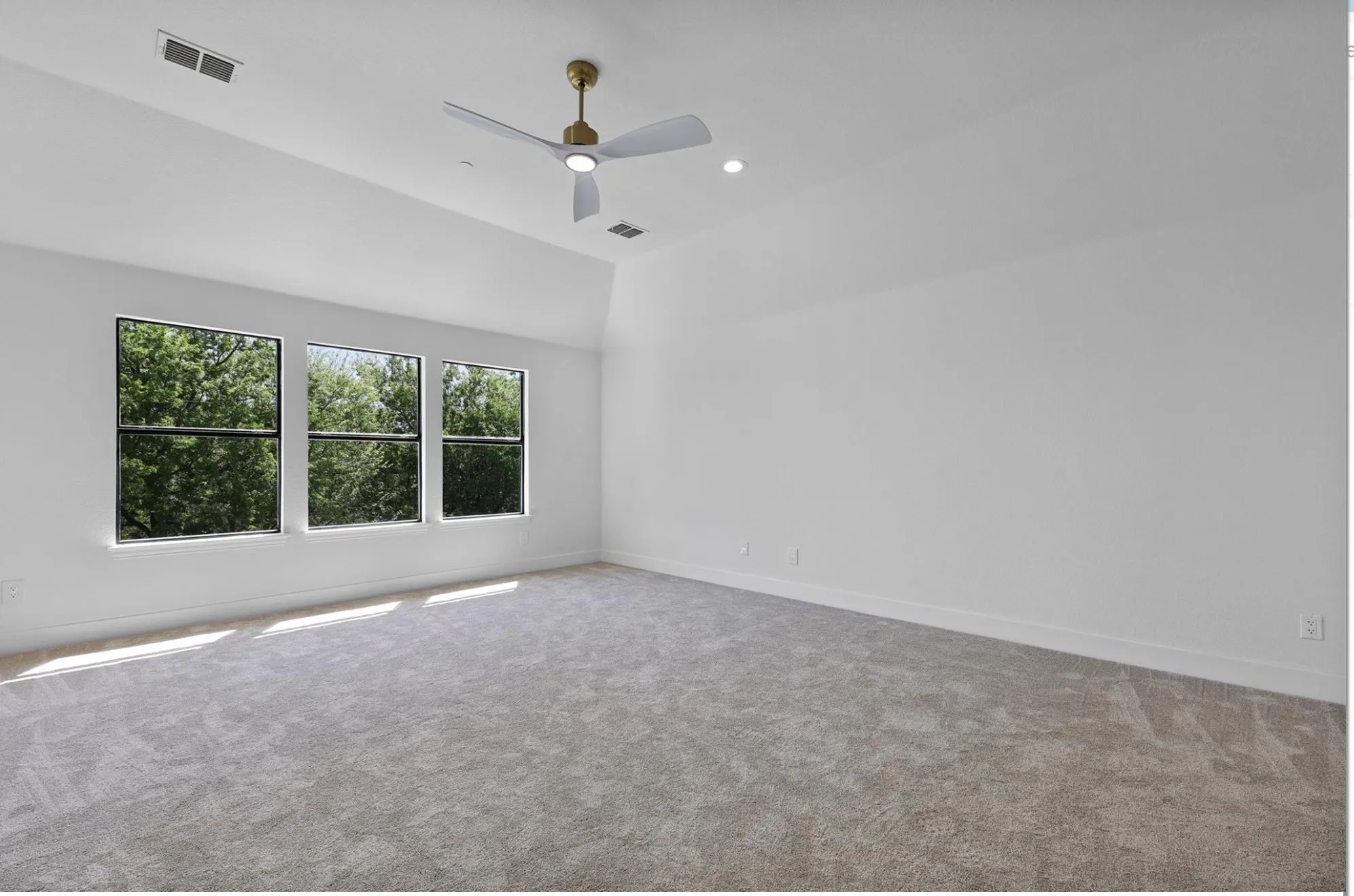 Vaulted ceiling, three rectangular windows, recessed lighting, ceiling fan, and light gray carpeting