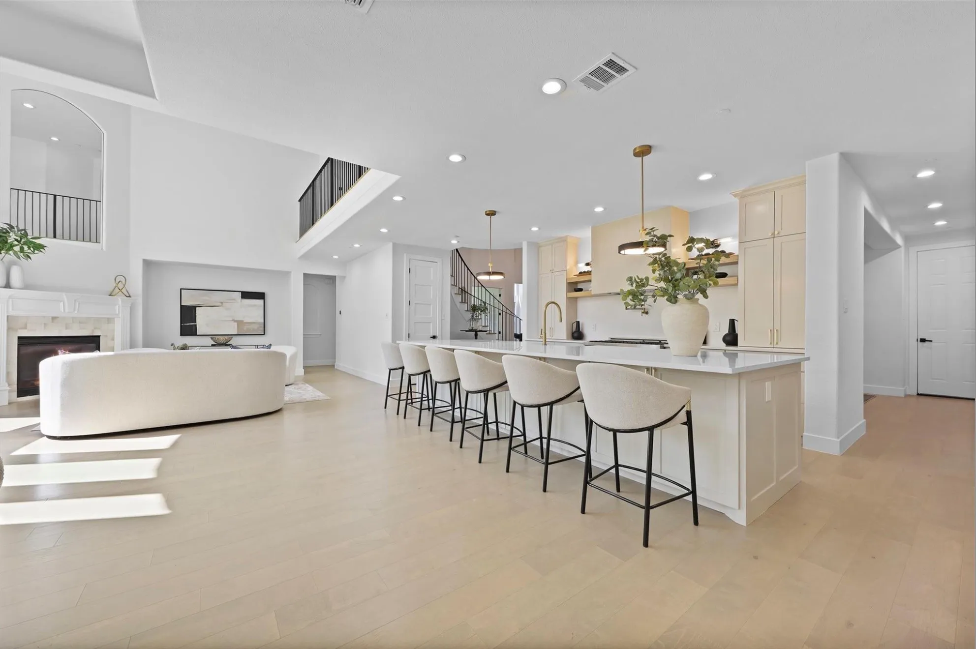 Vaulted ceilings with an arched balcony, recessed lighting, wood-finish flooring, a kitchen island with seating, and a built-in fireplace