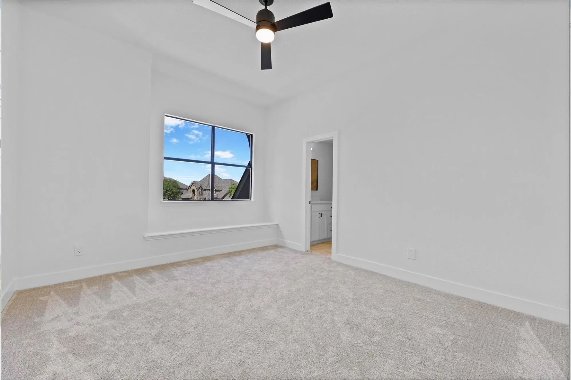 Light-colored carpeting, white walls, and a black ceiling fan with an integrated light fixture