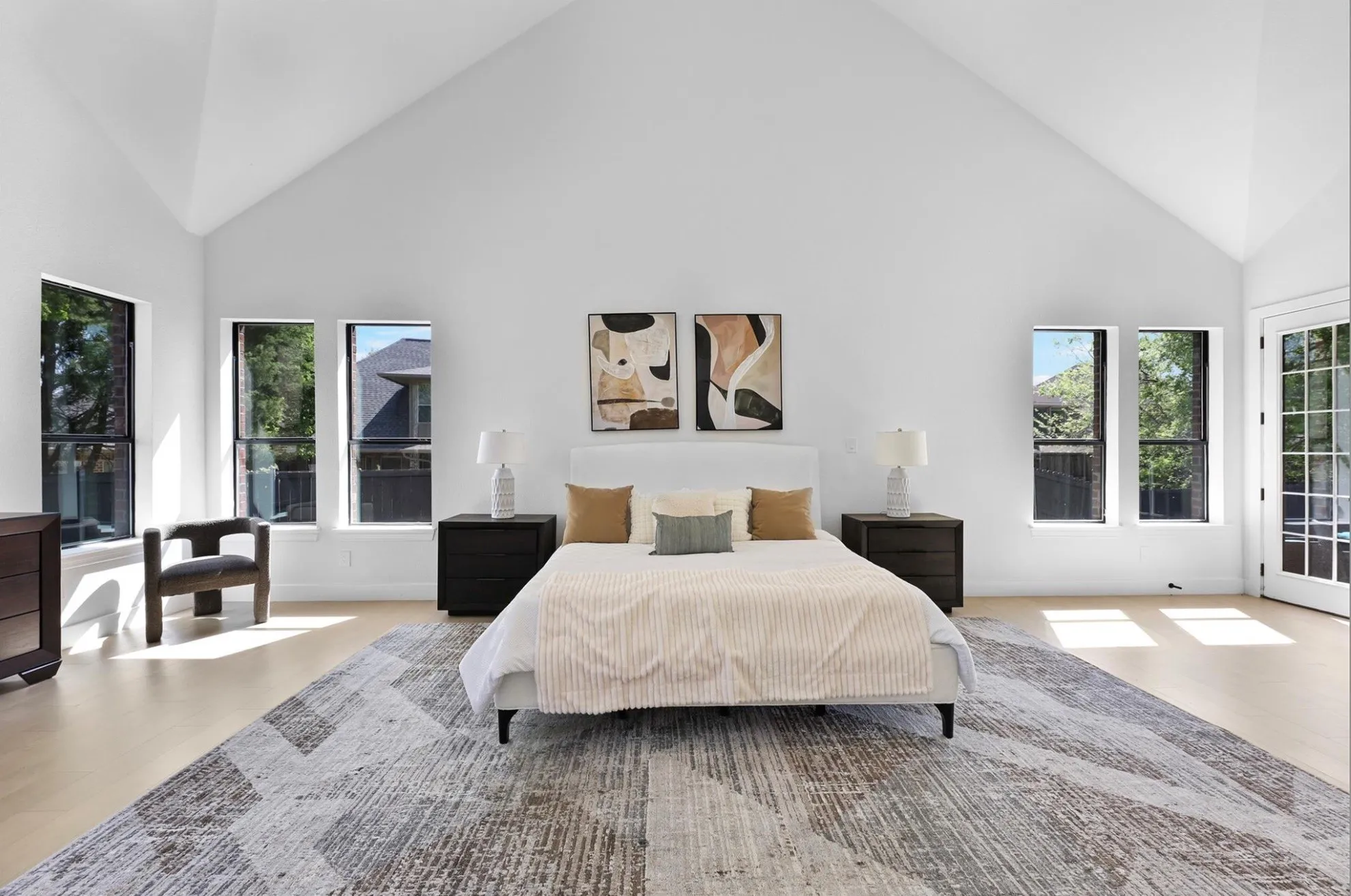 Vaulted ceiling, light wood-finish flooring, multiple windows, double French doors, and a contemporary ceiling fan