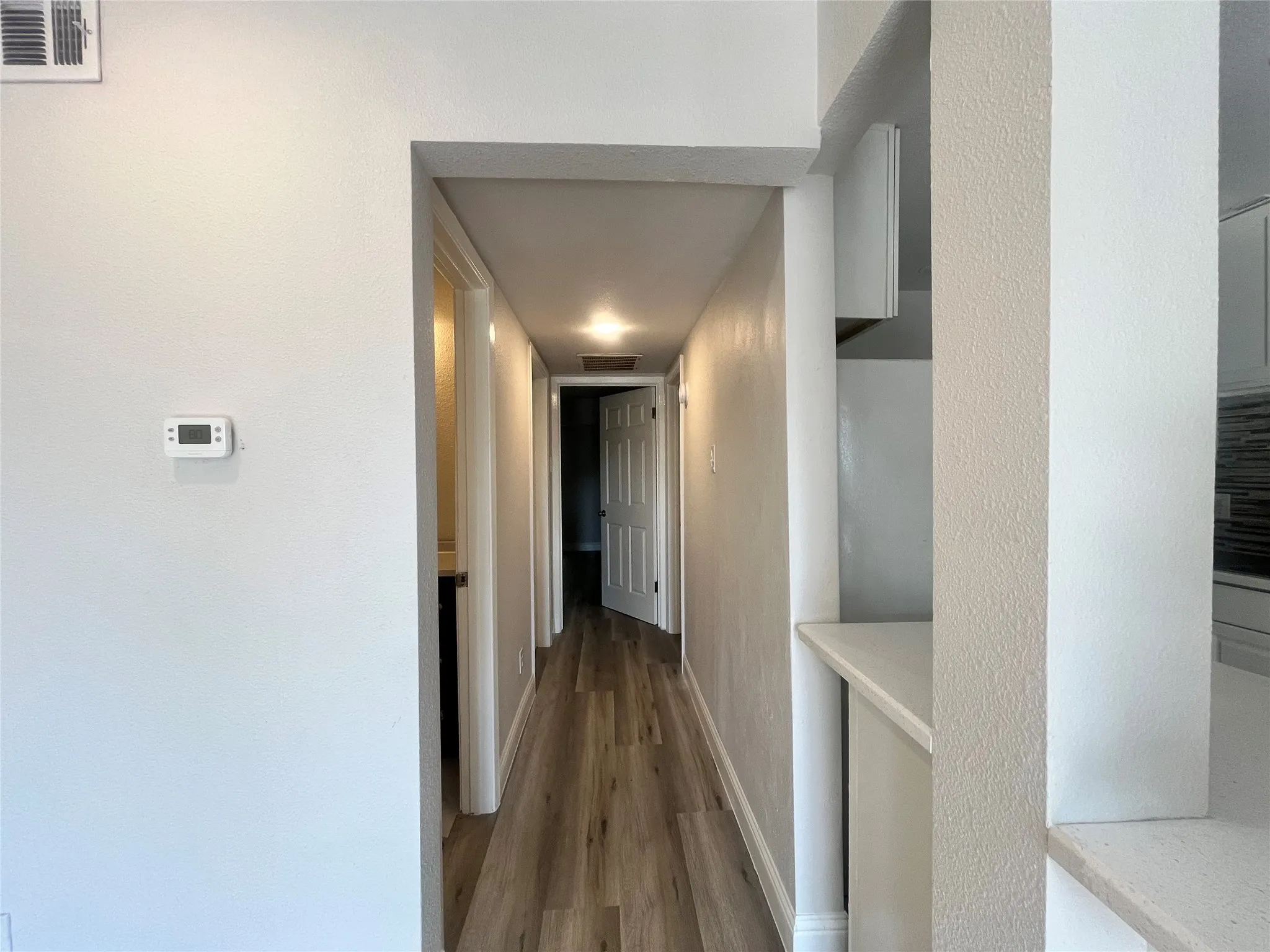 Hallway featuring wood-finish flooring, recessed lighting, and a neutral color palette