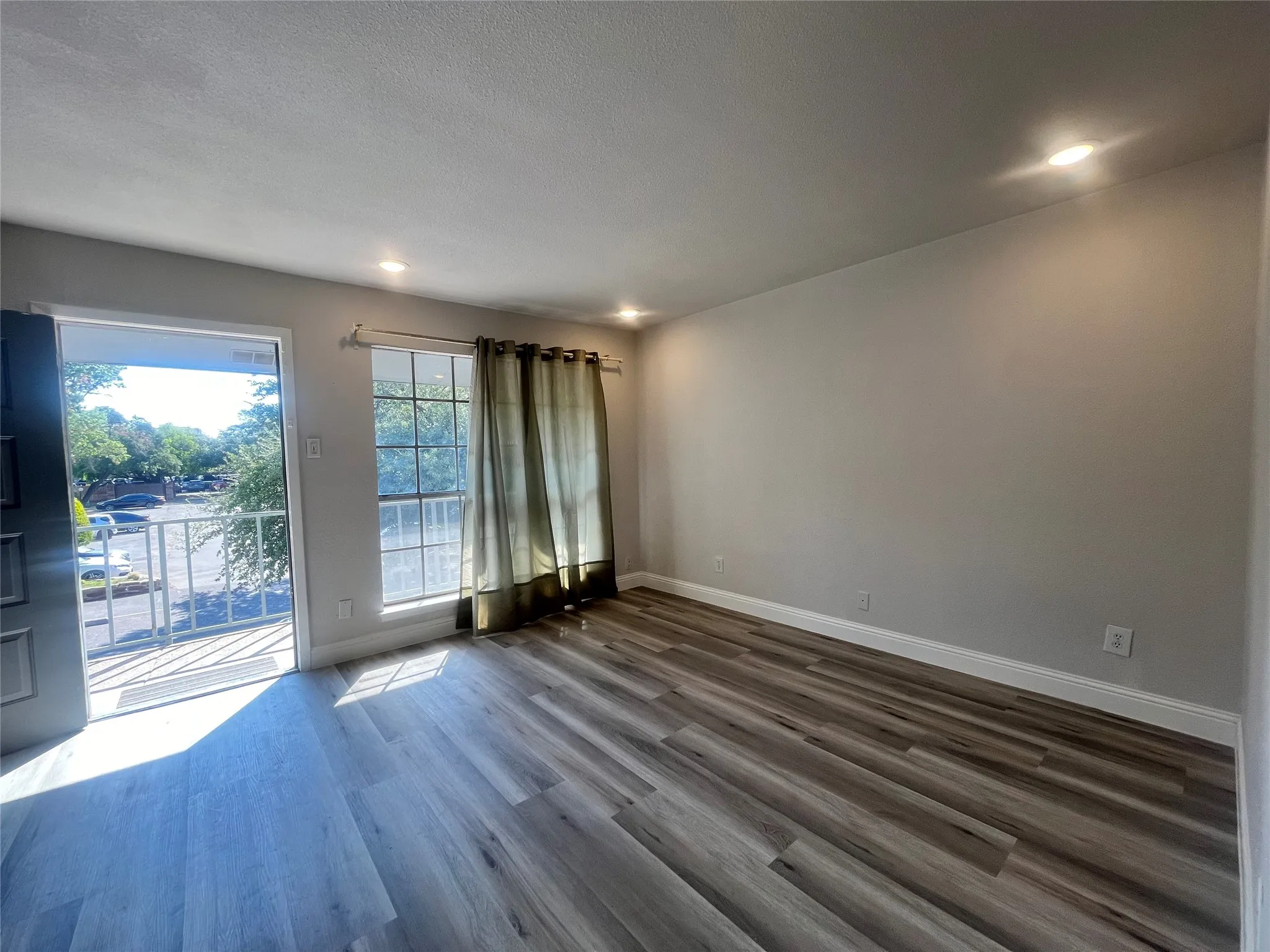 Spacious room featuring wood-finish flooring, recessed lighting, and a window with natural light