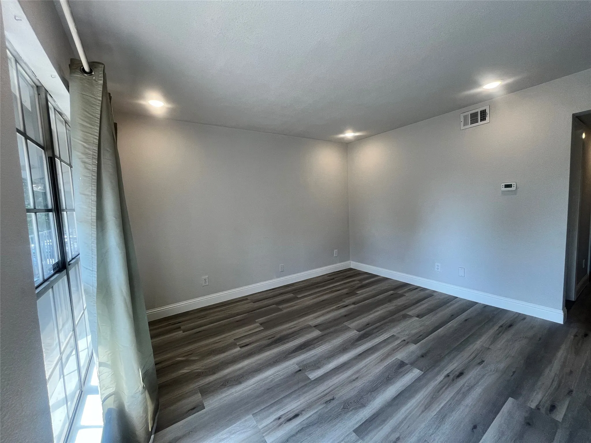 Recessed ceiling lighting, wood-finish flooring, and a large window