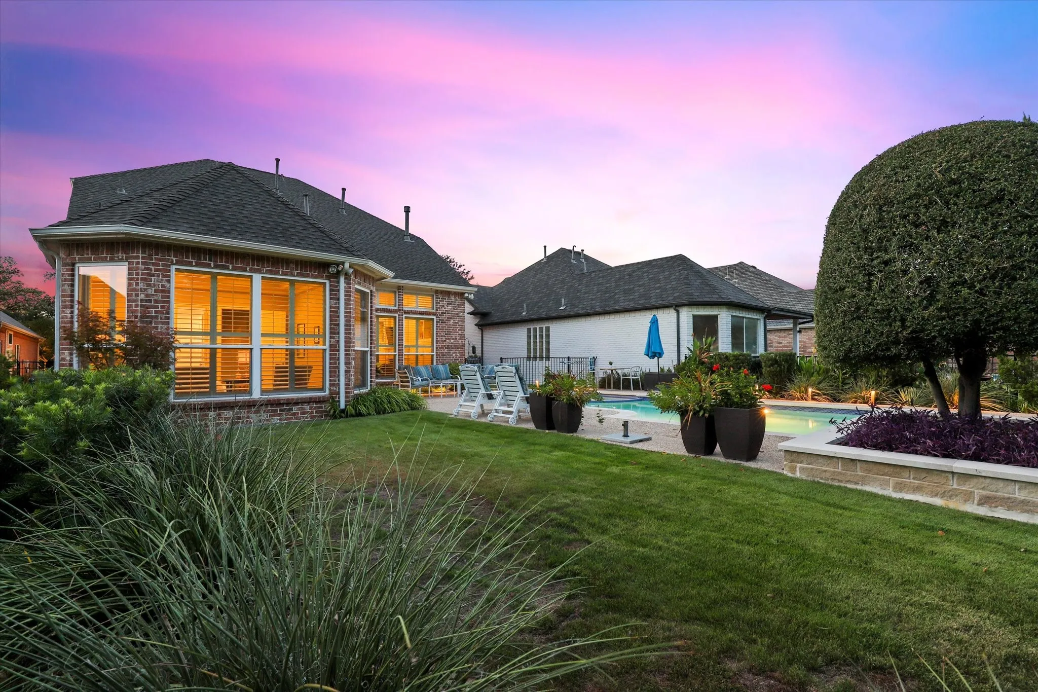 Landscaped grounds and an adjoining lawn complement the poolside patio and the home’s expansive windows, while offering room for pets and play.