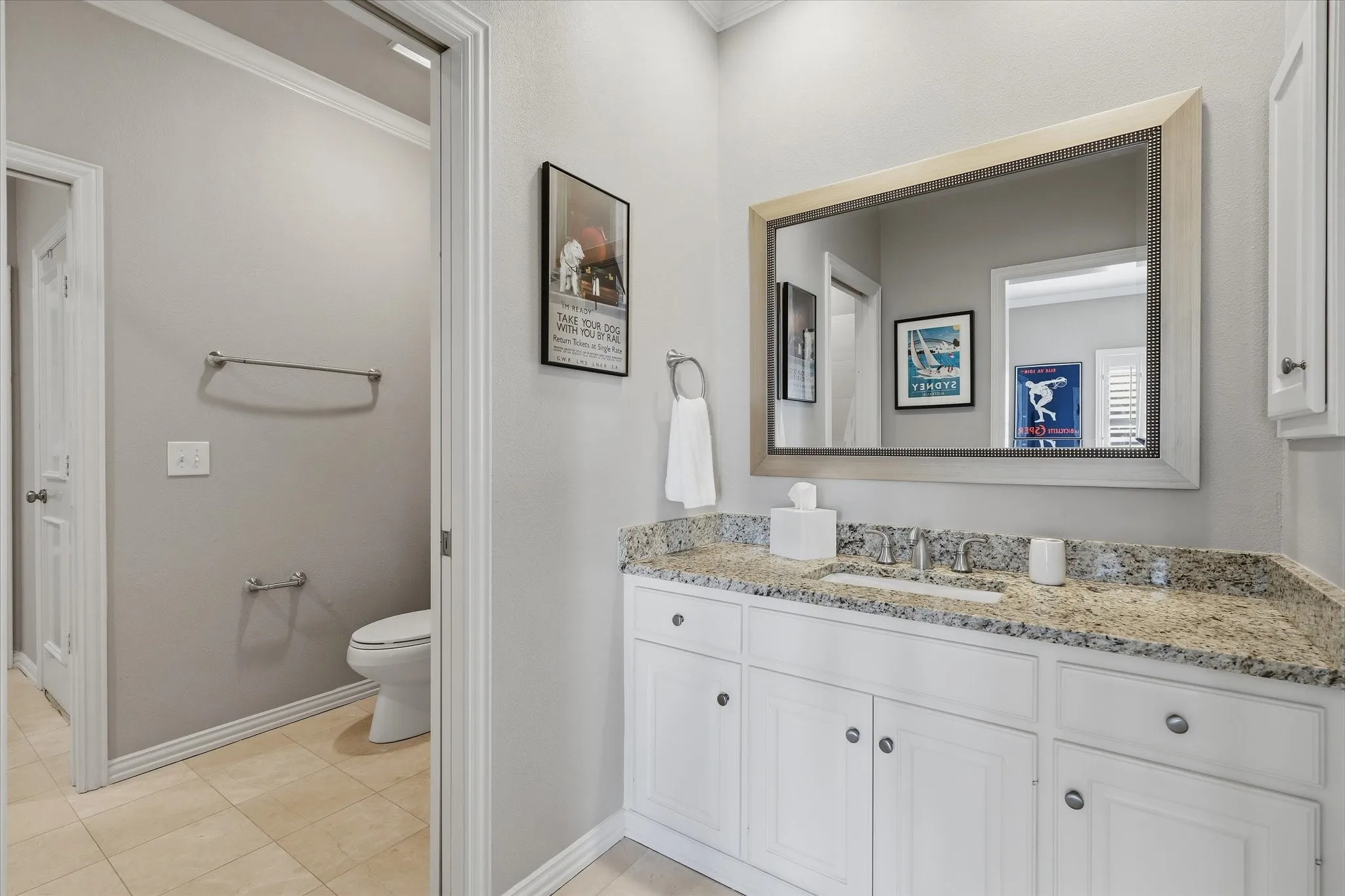 The updated Jack-and-Jill bath features white cabinetry, a stone-topped vanity and a separate water closet and bath/shower area.