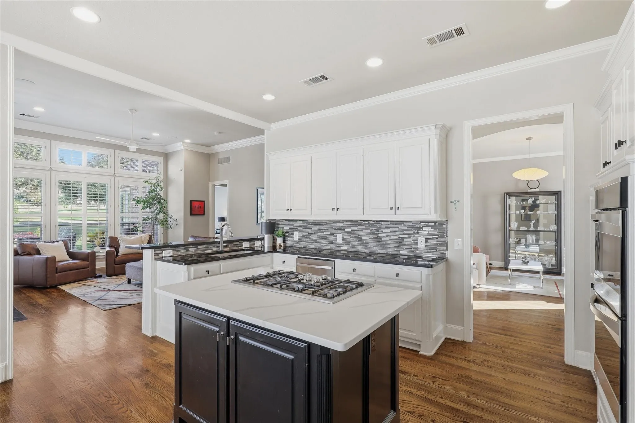 Opening to the family room, the kitchen balances classic white cabinets with a contrasting island and stainless-steel appliances.