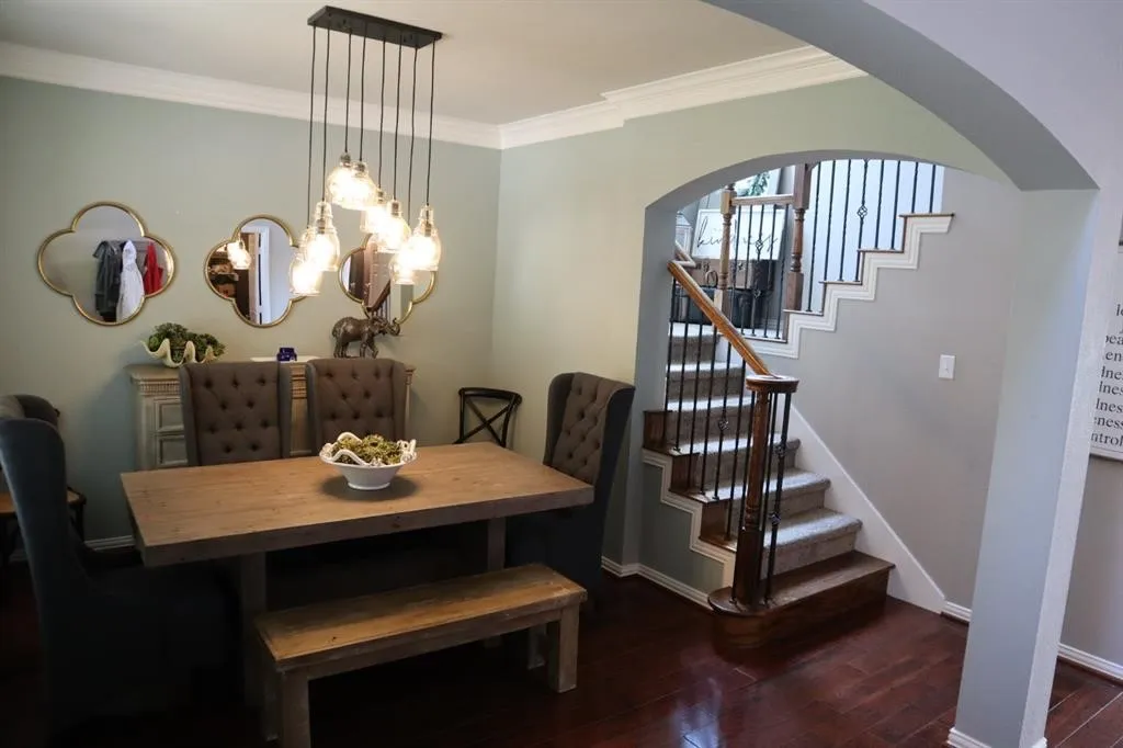 Dining area featuring wood-finish flooring, a multi-bulb pendant light fixture, and crown molding