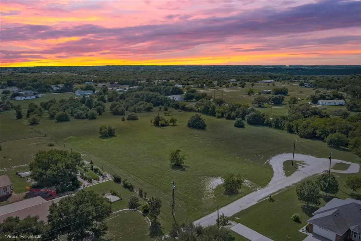 Expansive green space with scattered mature trees and residential structures