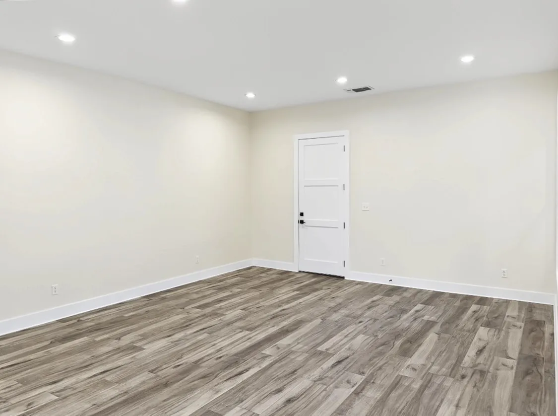 Recessed ceiling lighting, wood-finish flooring, white trim, and a white panel door