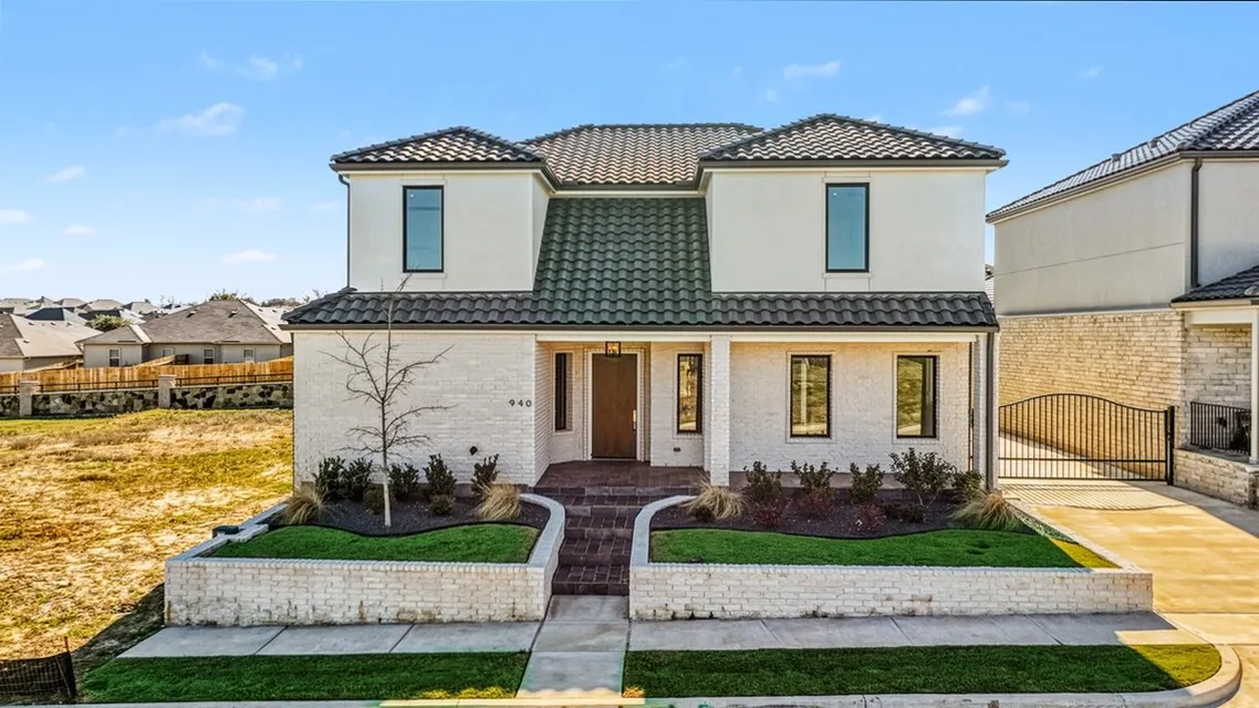 Stucco and brick exterior with a tile roof, featuring a brick paver walkway and a side-gated driveway