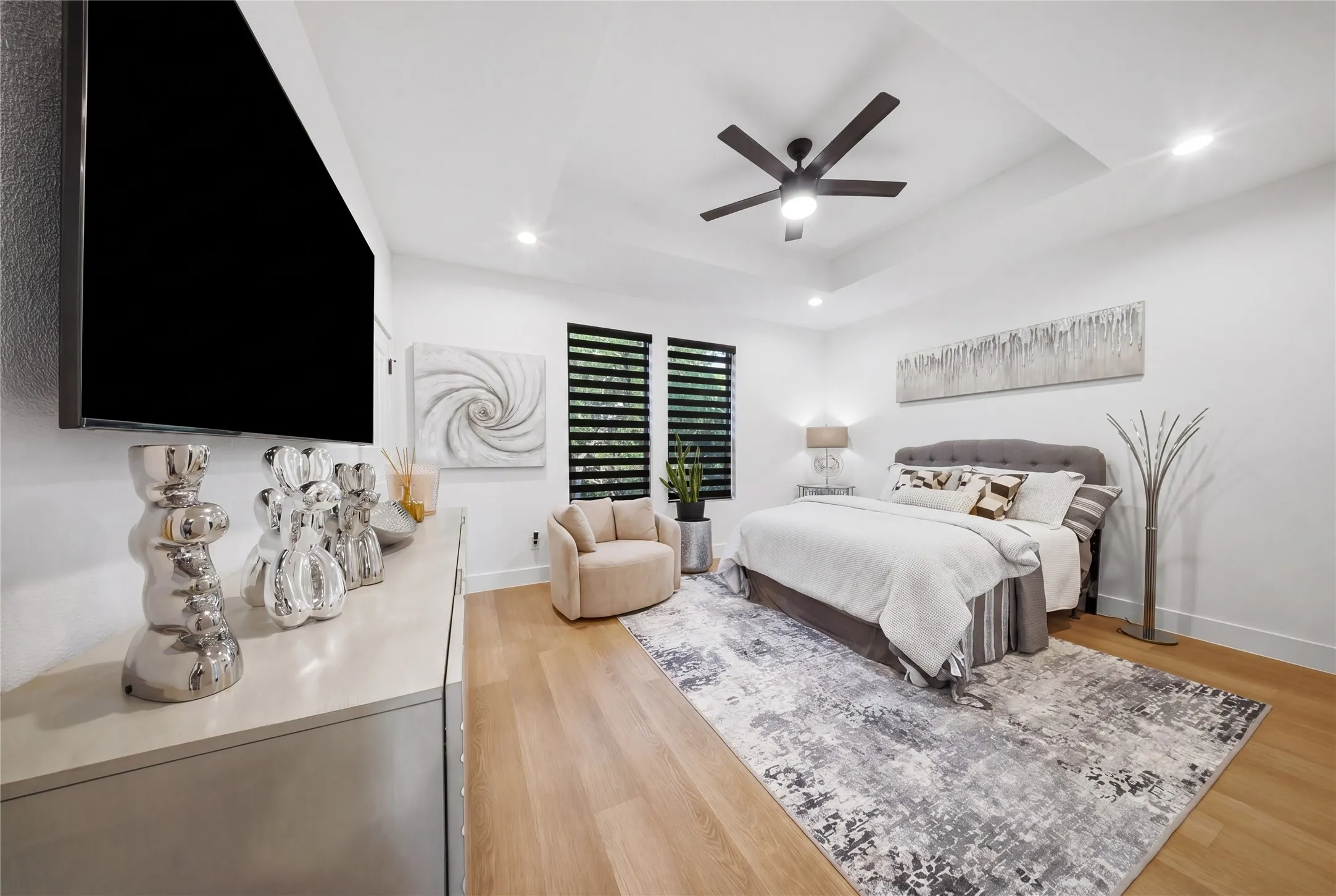 Tray ceiling with recessed lighting and a ceiling fan, wood-finish flooring, and a wall-mounted television