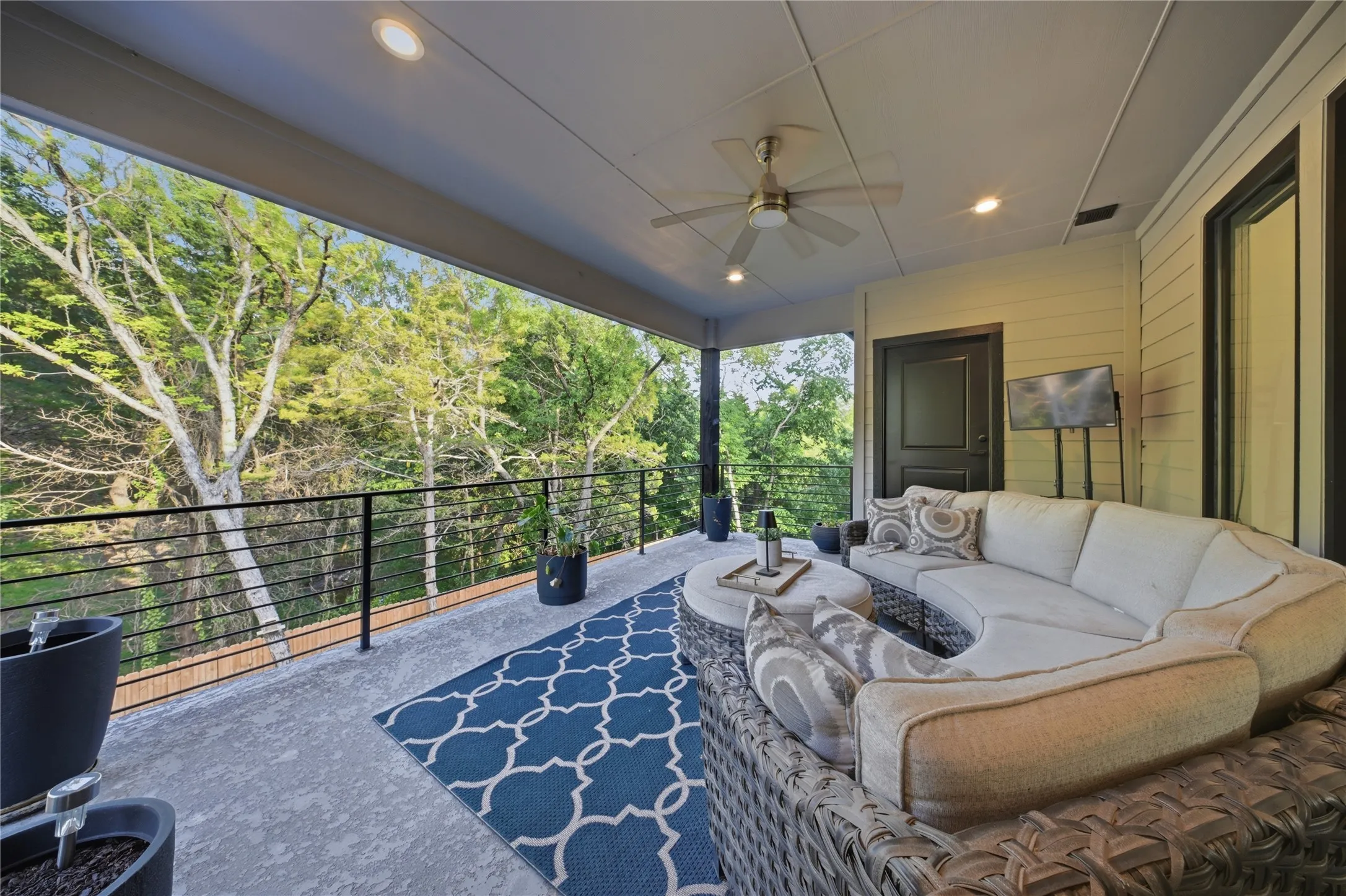 Covered outdoor space featuring a ceiling fan, recessed lighting, and a dark-framed door