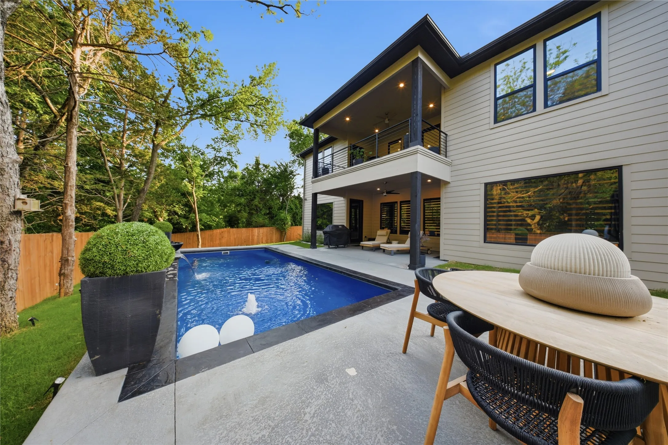 Contemporary exterior with horizontal siding, an upper-level balcony, a lower-level covered patio, a rectangular swimming pool, and a concrete patio