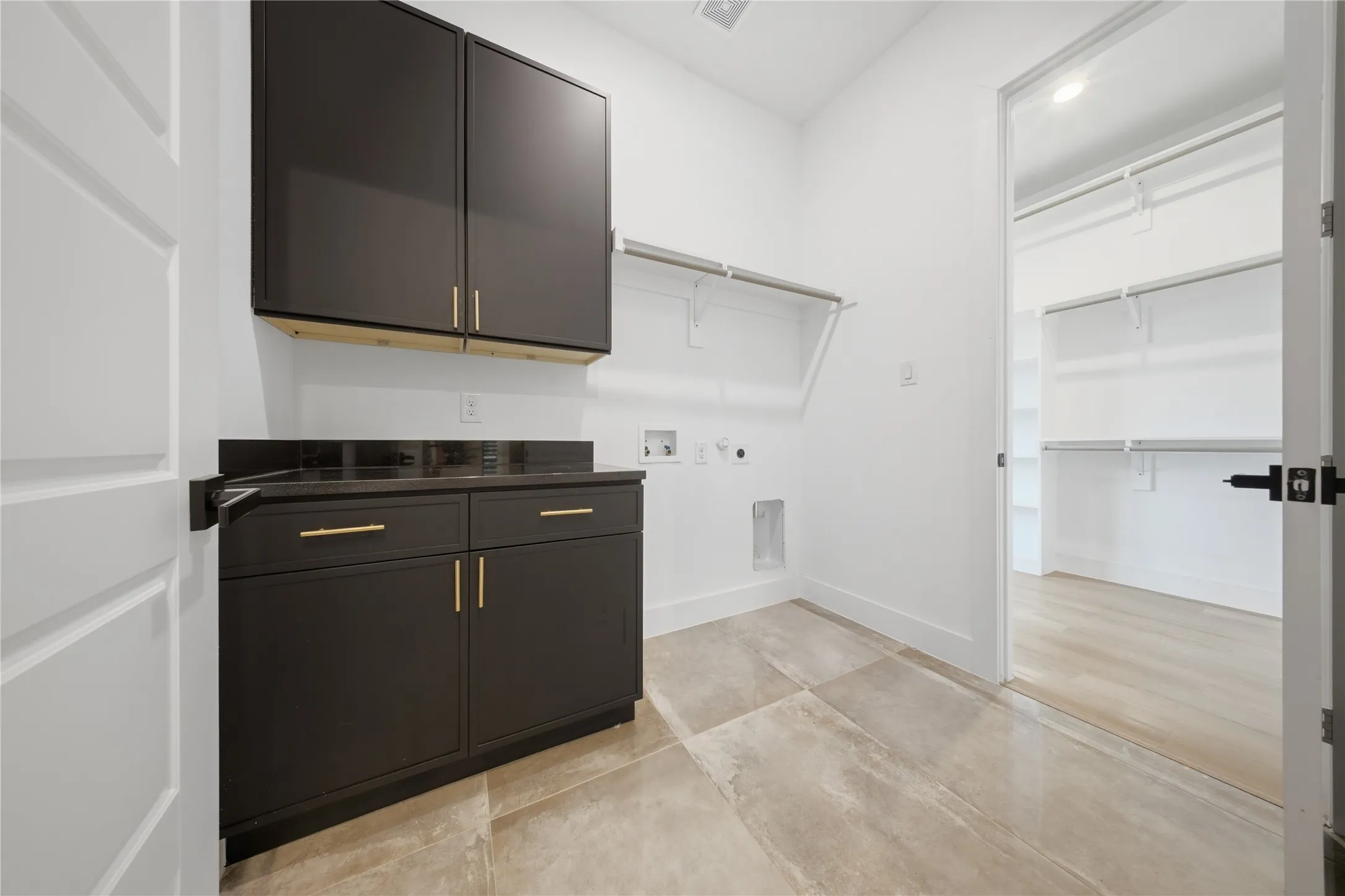 Built-in dark cabinetry with gold-tone hardware, dark countertop, and tiled flooring