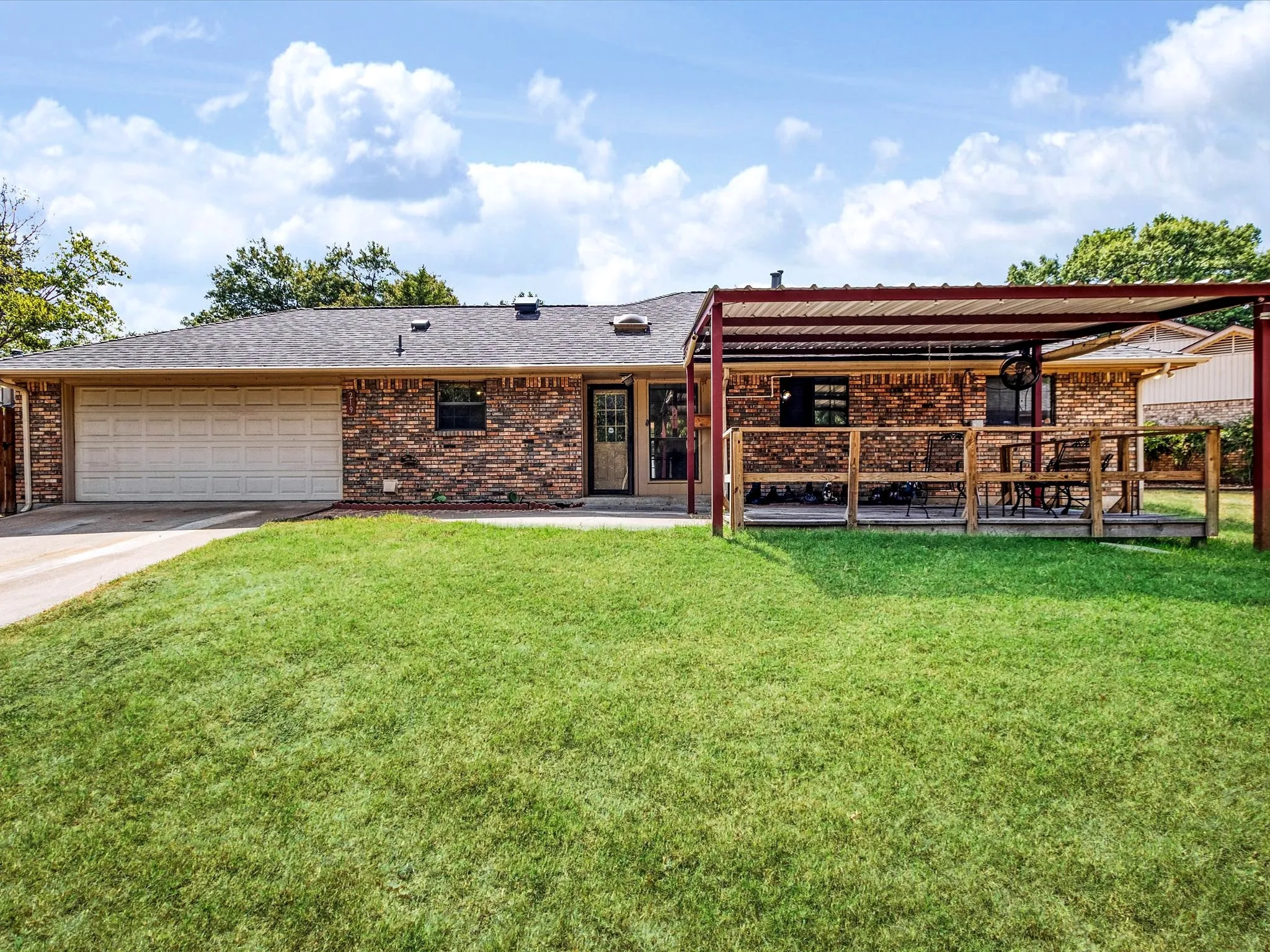 Brick exterior with an attached garage, covered patio, and a fenced yard