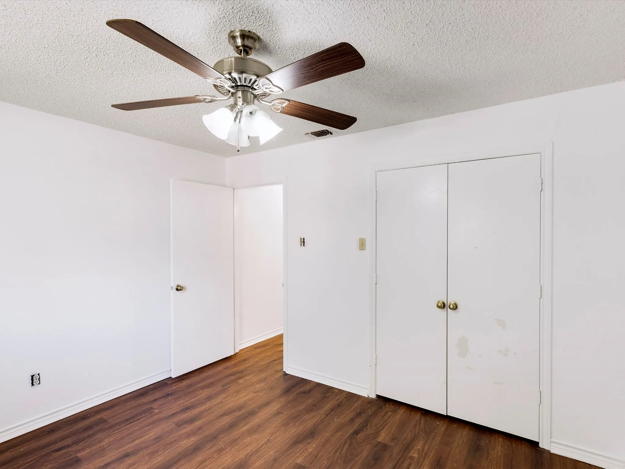Wood-finish flooring, white walls, and a ceiling fan with integrated lighting