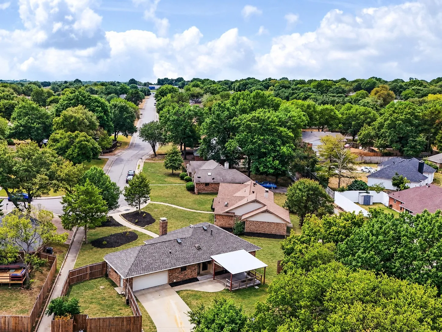 Brick exterior residence with an attached garage, covered patio, and fenced yard