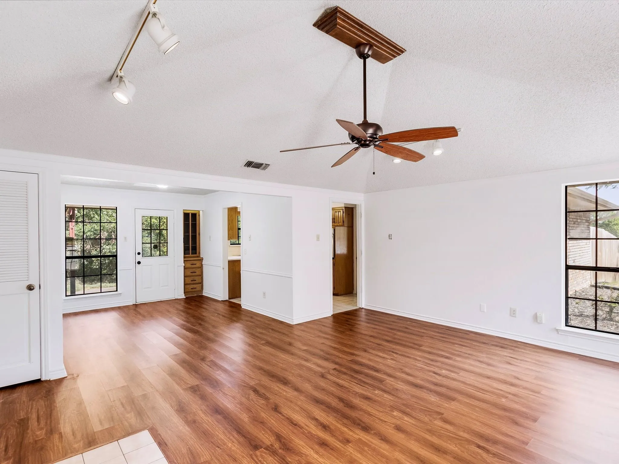 Vaulted ceiling with a wood-finish ceiling fan, recessed lighting, and track lighting
