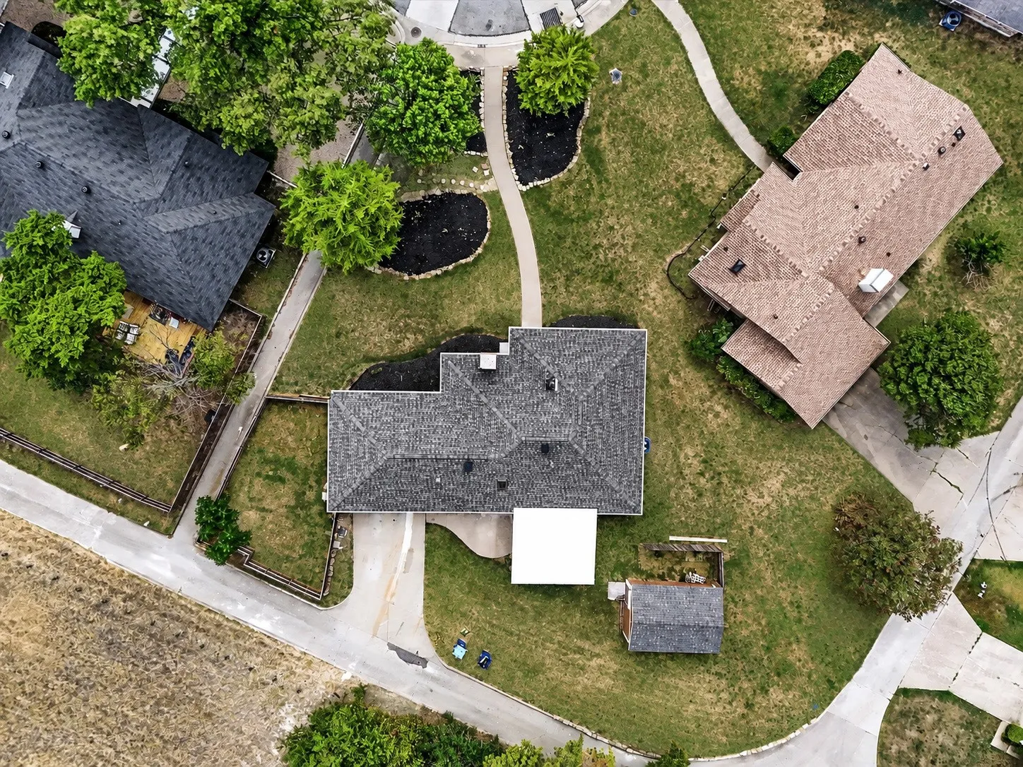 Expansive lot featuring a detached storage shed, mature trees, and a paved driveway