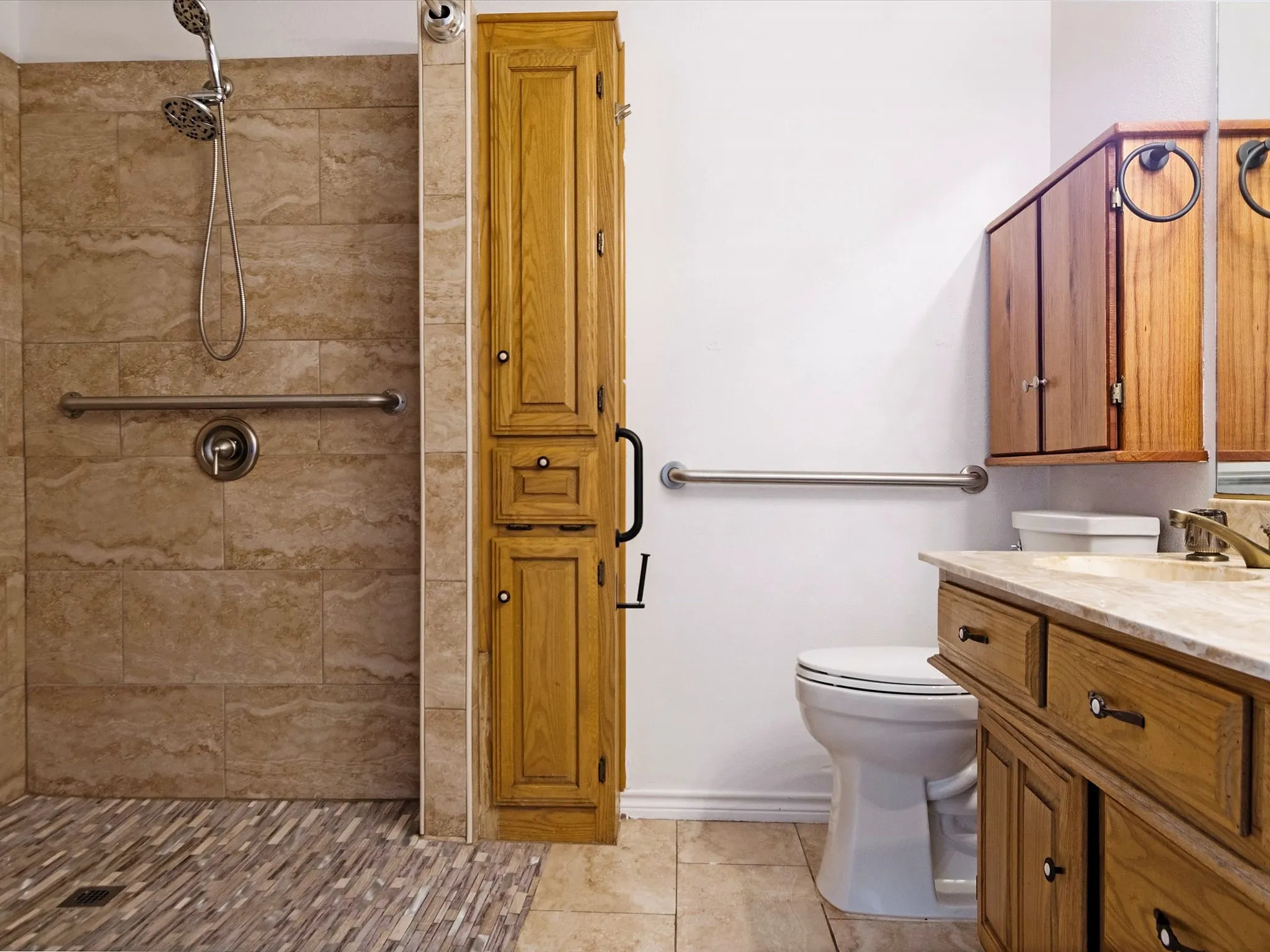 Walk-in shower with natural-toned wall tile and multi-toned floor tile