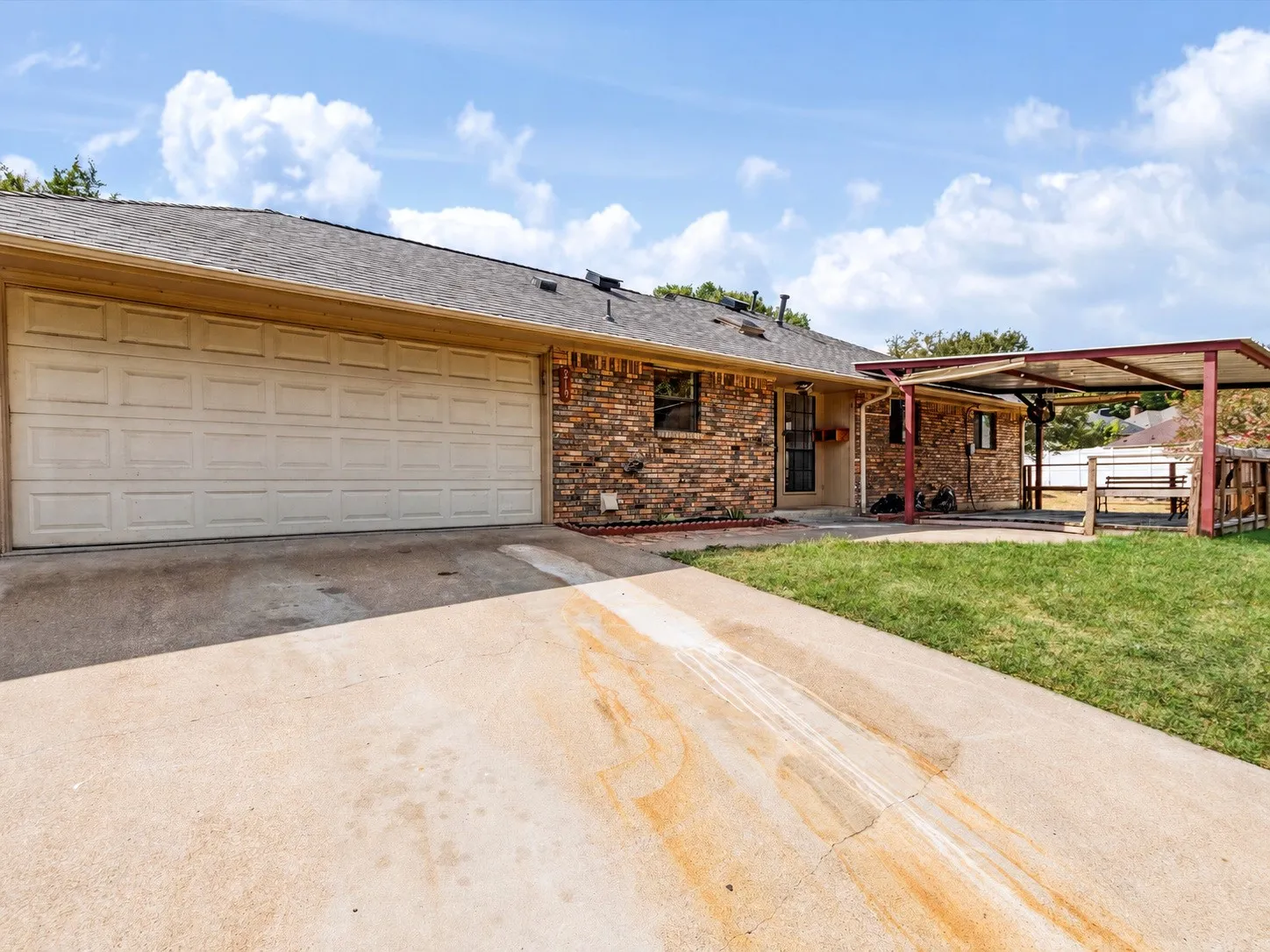 Brick exterior with a covered patio, attached carport, concrete driveway, and a two-car garage