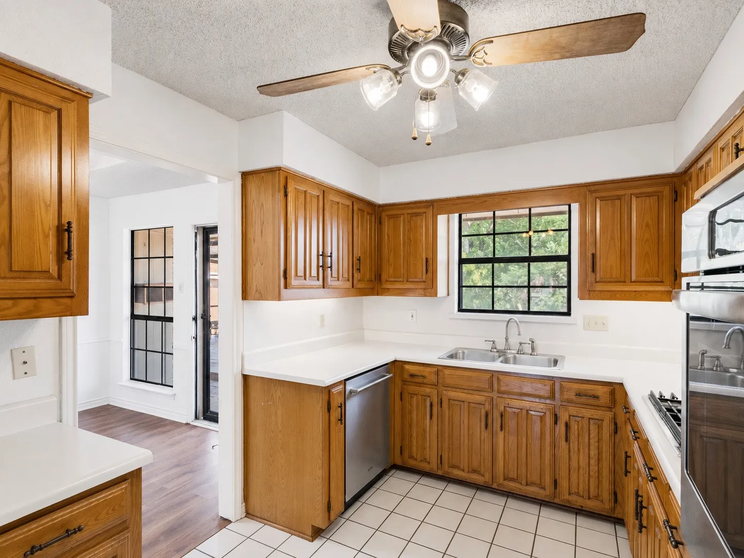 Kitchen featuring wood cabinetry, white countertops, a double basin sink, and tile flooring