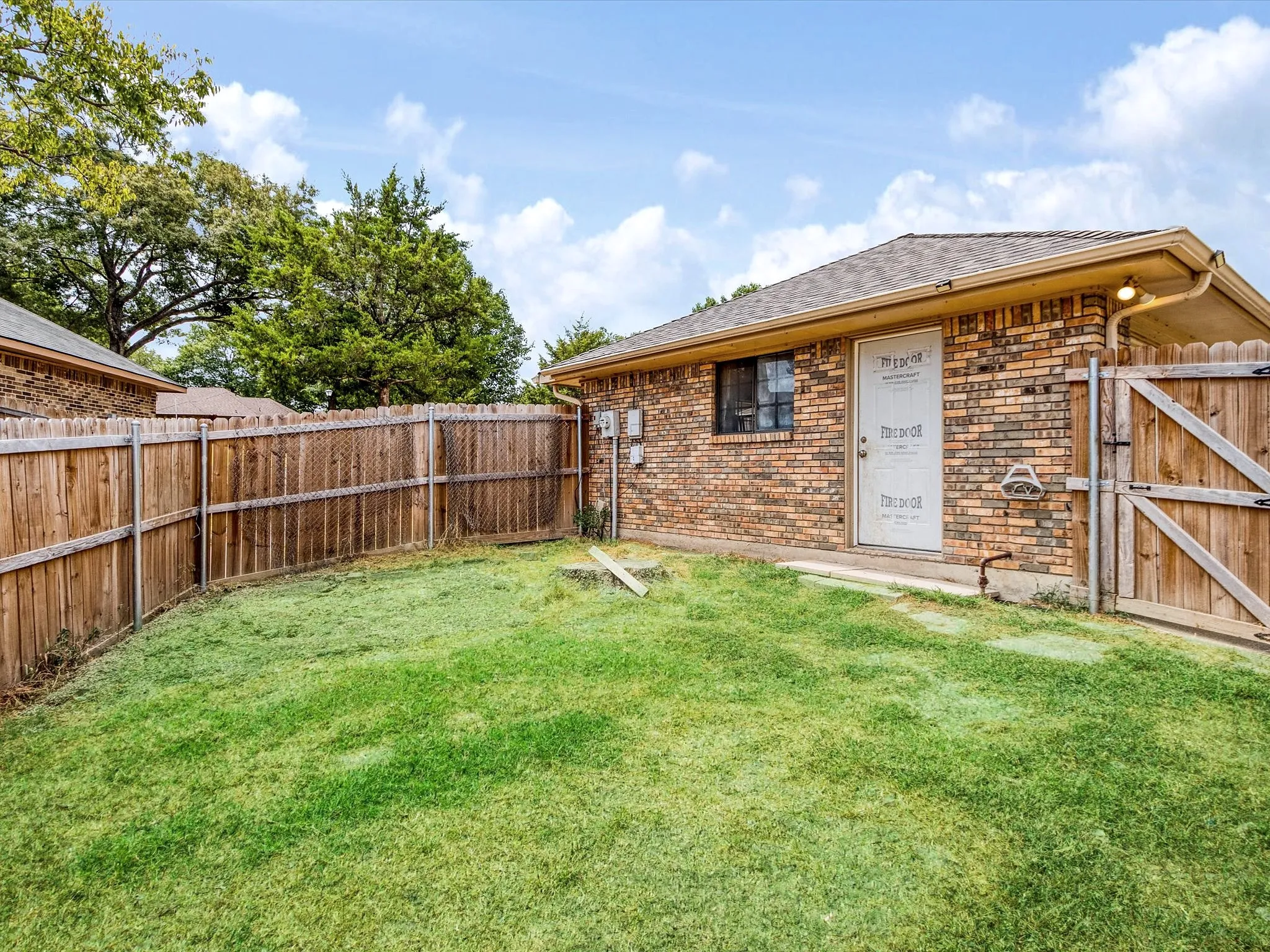 Brick exterior with a gabled roof and wood fence