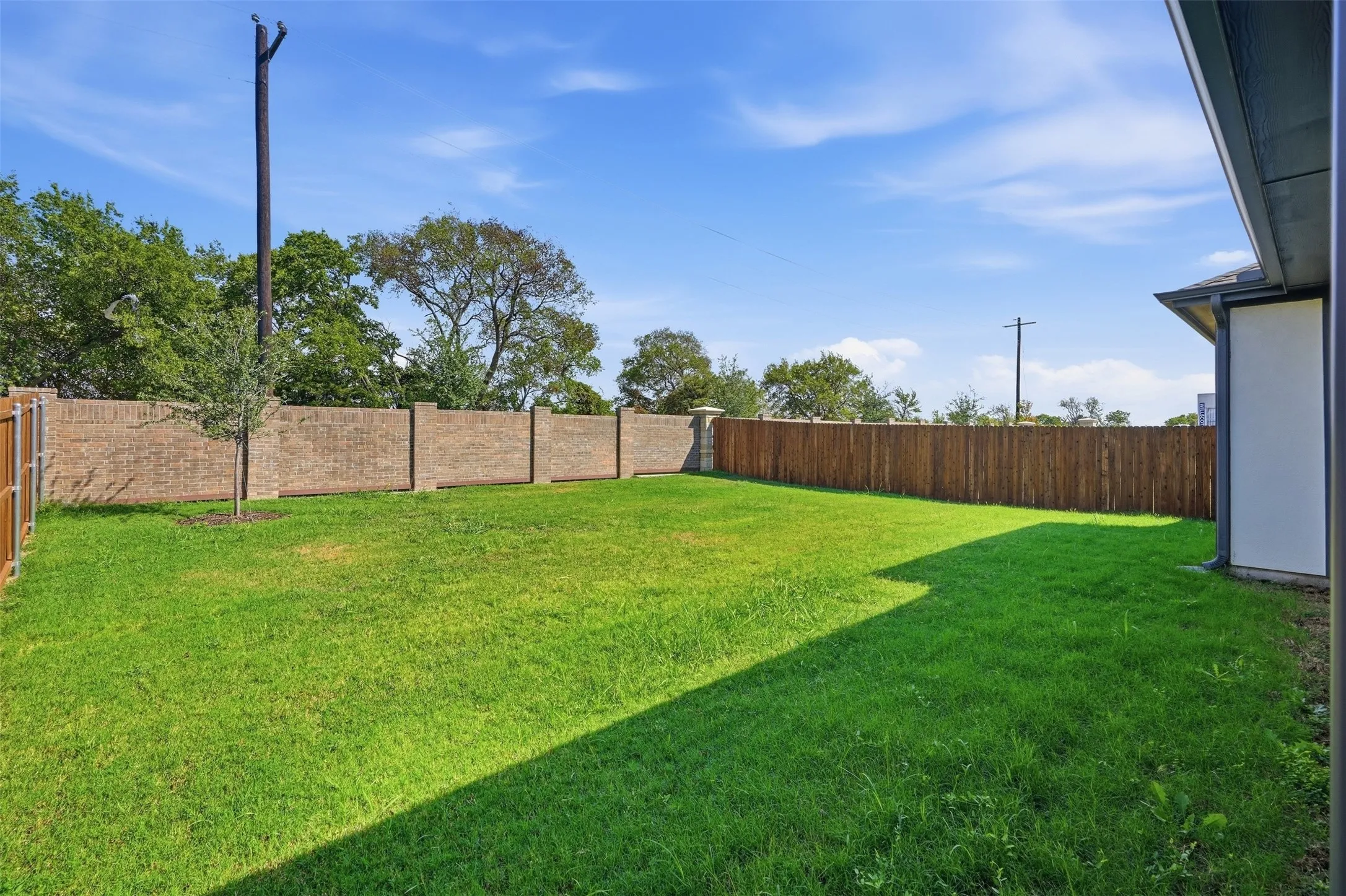 Expansive backyard featuring a lush lawn, a full brick perimeter fence, and a wood privacy fence