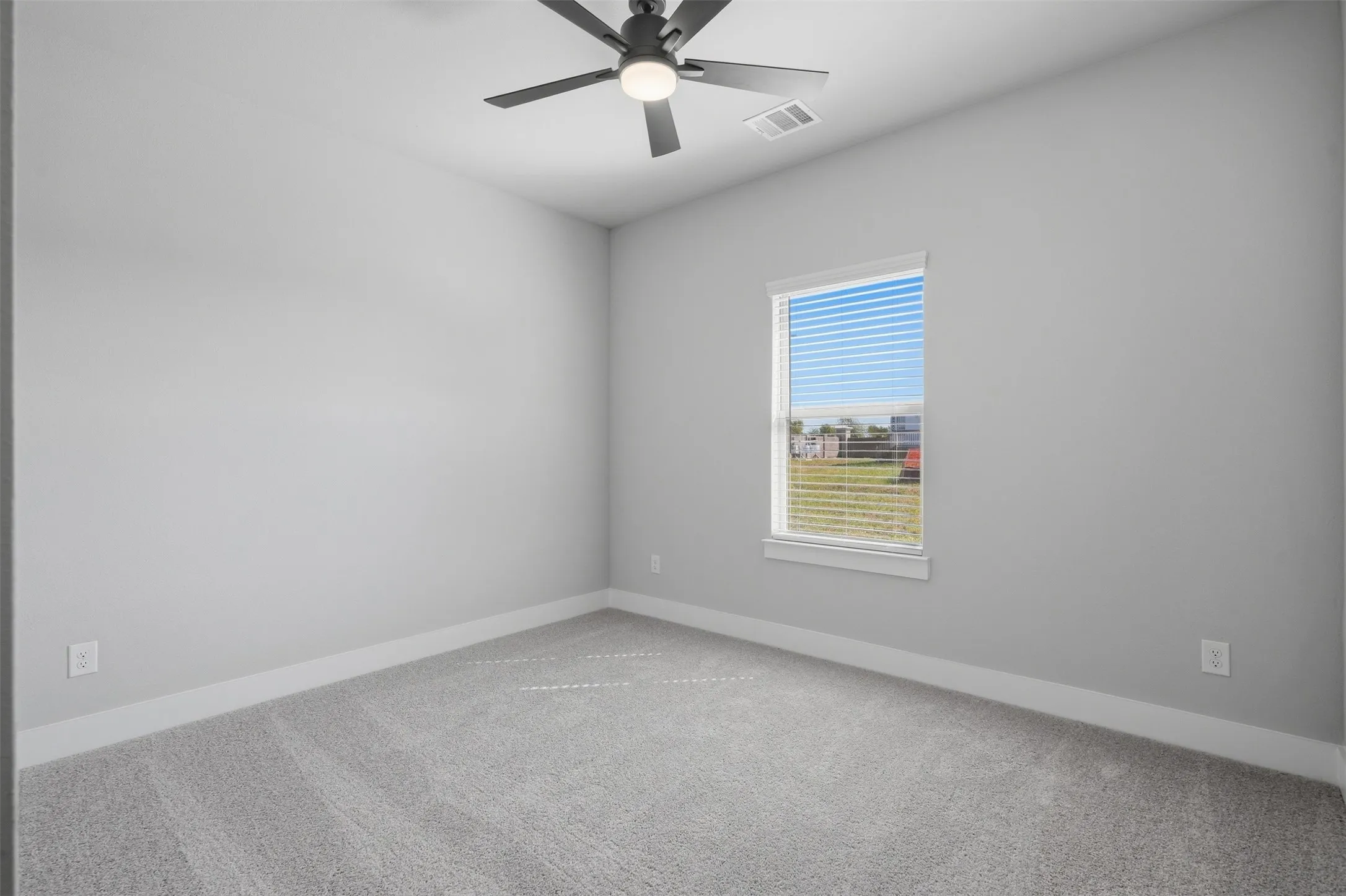 Neutral wall paint, ceiling fan with integrated lighting, single window with blinds, and gray carpet flooring
