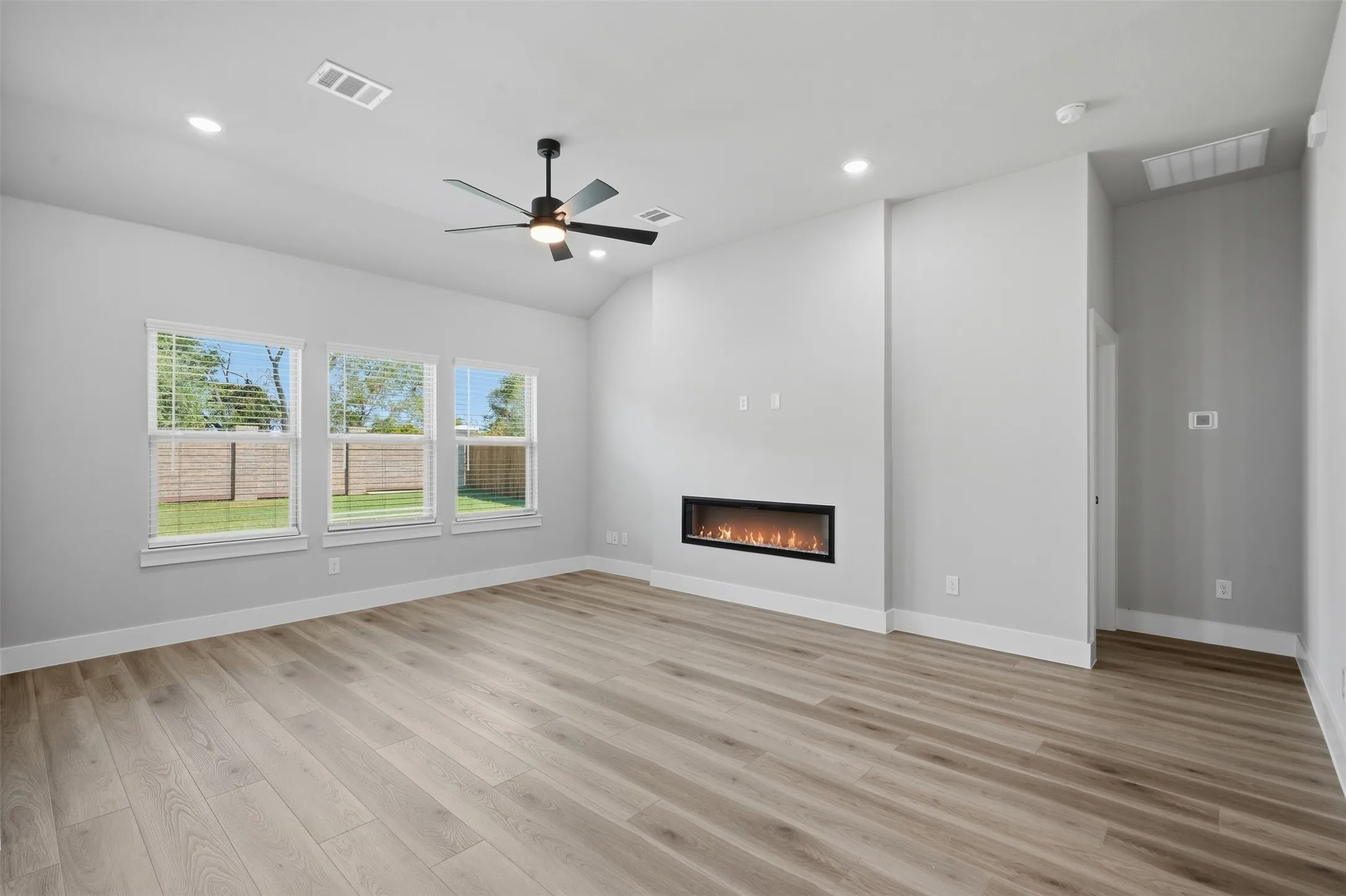 Spacious room featuring wood-finish flooring, an electric fireplace, a ceiling fan, and recessed lighting