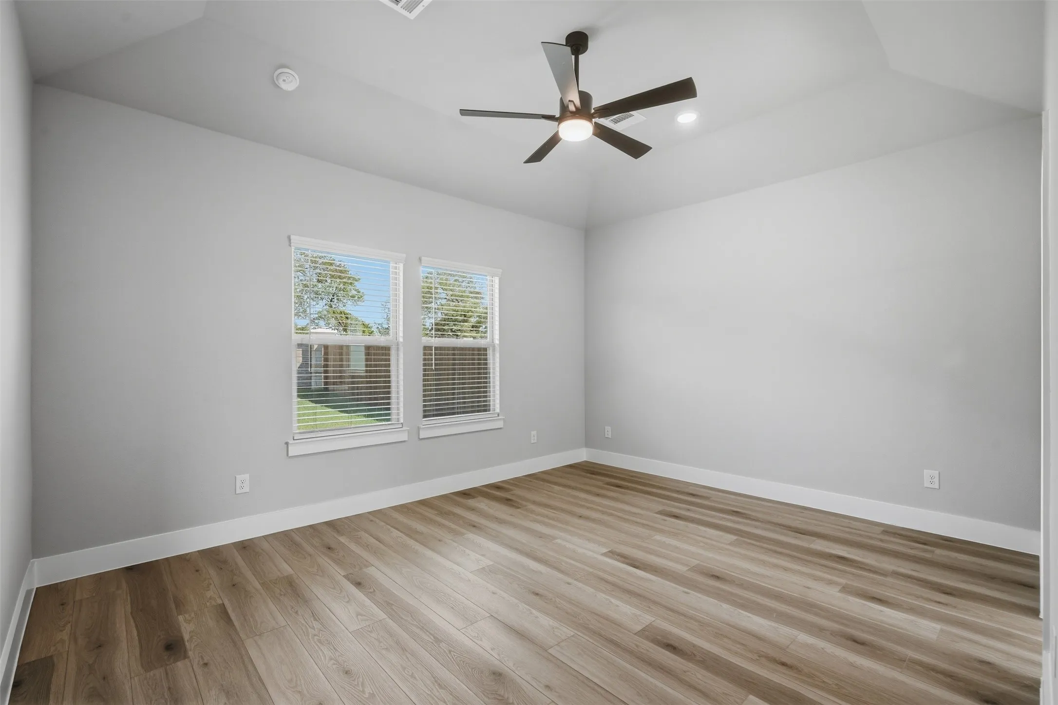 Vaulted ceiling, wood-finish flooring, recessed lighting, and a ceiling fan with integrated lighting