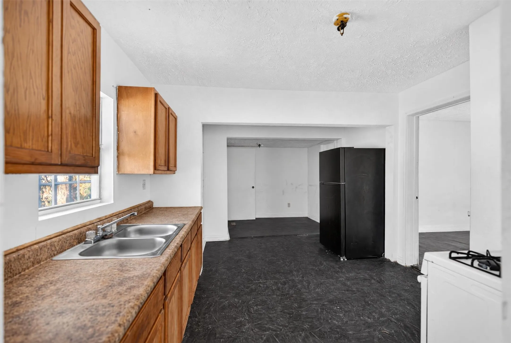 Kitchen featuring wood-finish cabinetry, a dual basin stainless steel sink, and a black refrigerator