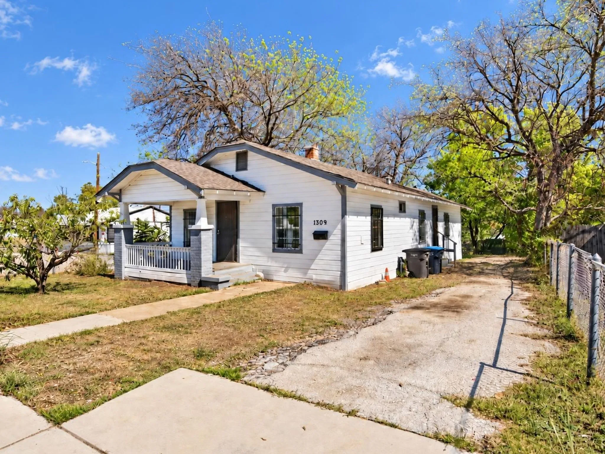 White exterior with dark trim windows, covered front porch, and a paved driveway