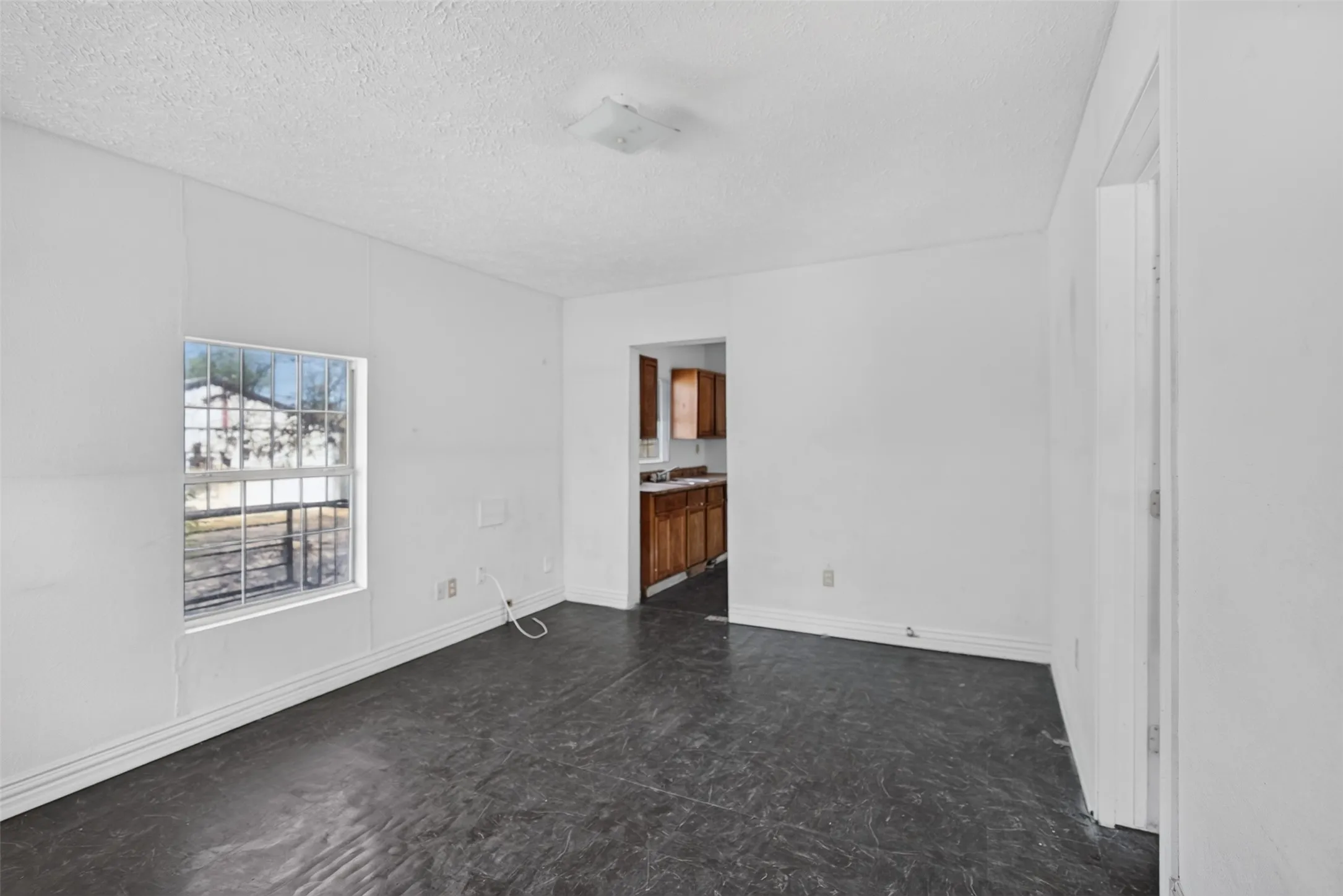 White walls, dark-toned flooring, and a window with security bars