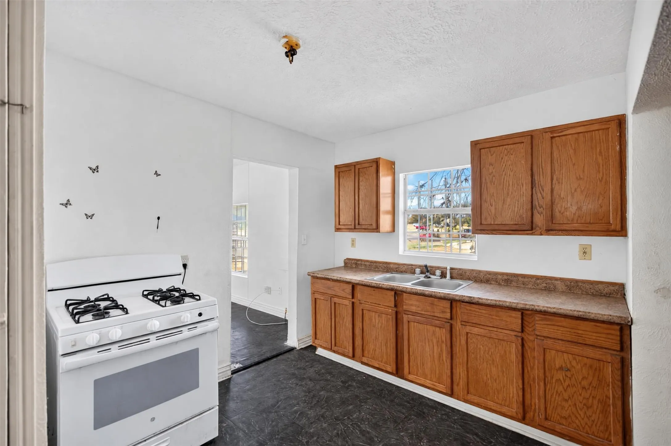 Kitchen featuring wood cabinetry, laminate countertops, a double basin sink, and a white gas range