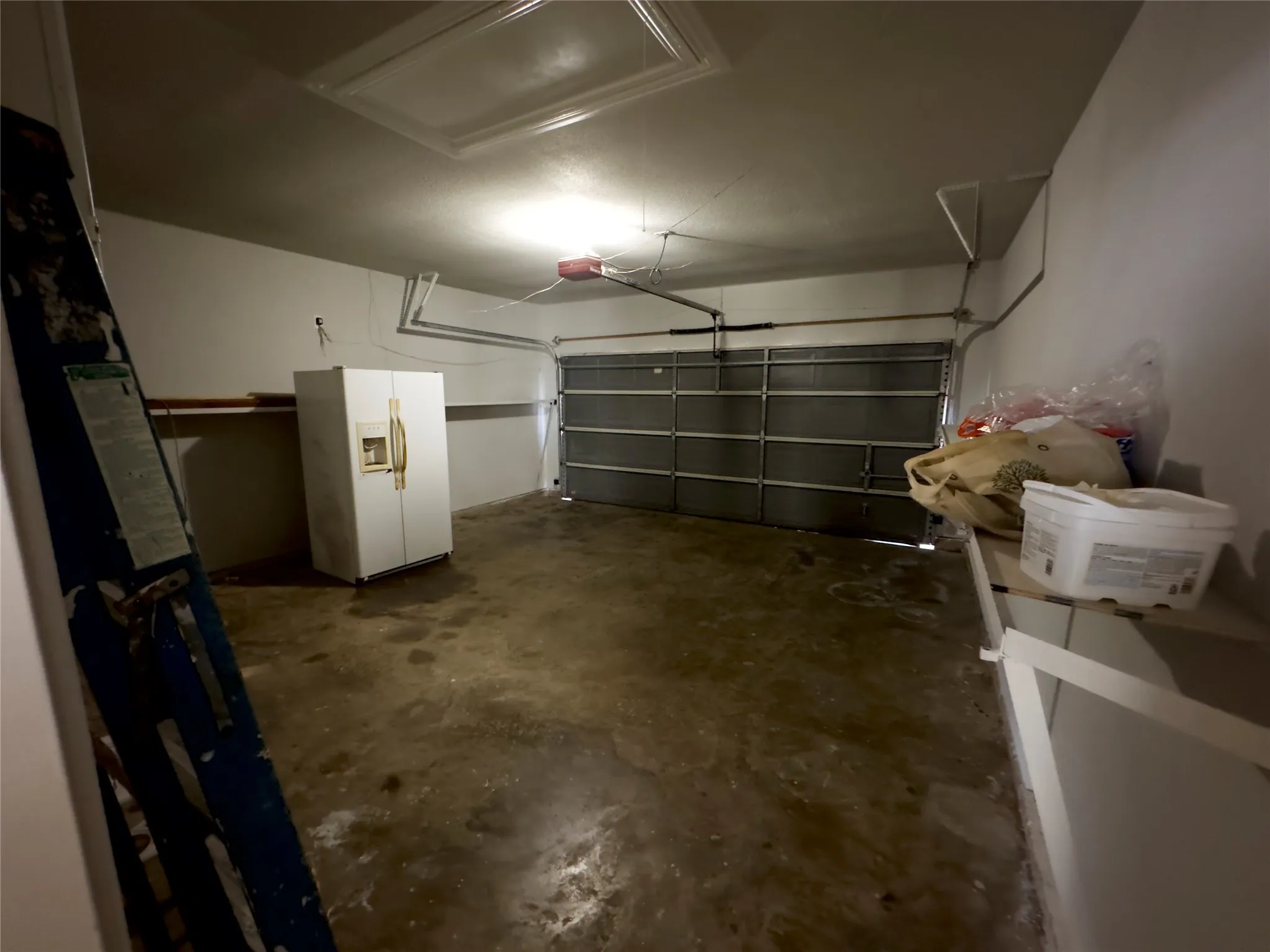 Garage with white fridge with ice dispenser and a garage door opener