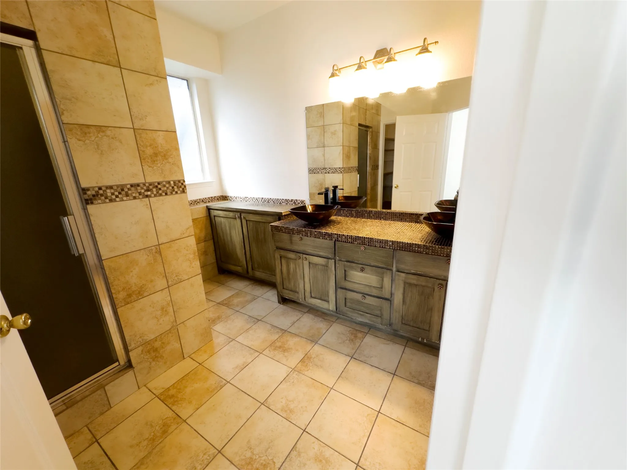 Bathroom featuring double vanity, light tile patterned floors, and tile walls