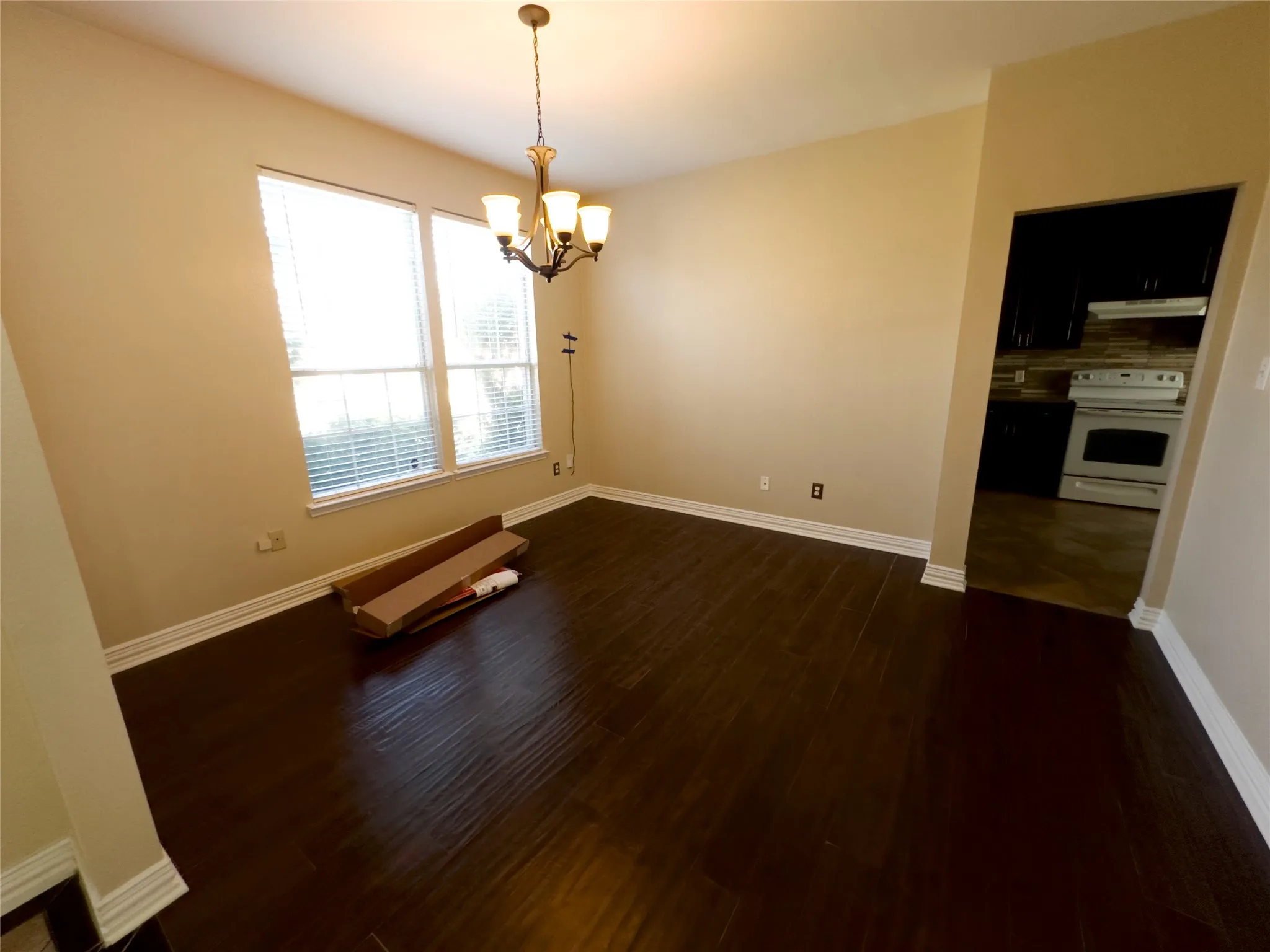 Unfurnished room with dark wood-type flooring and a chandelier