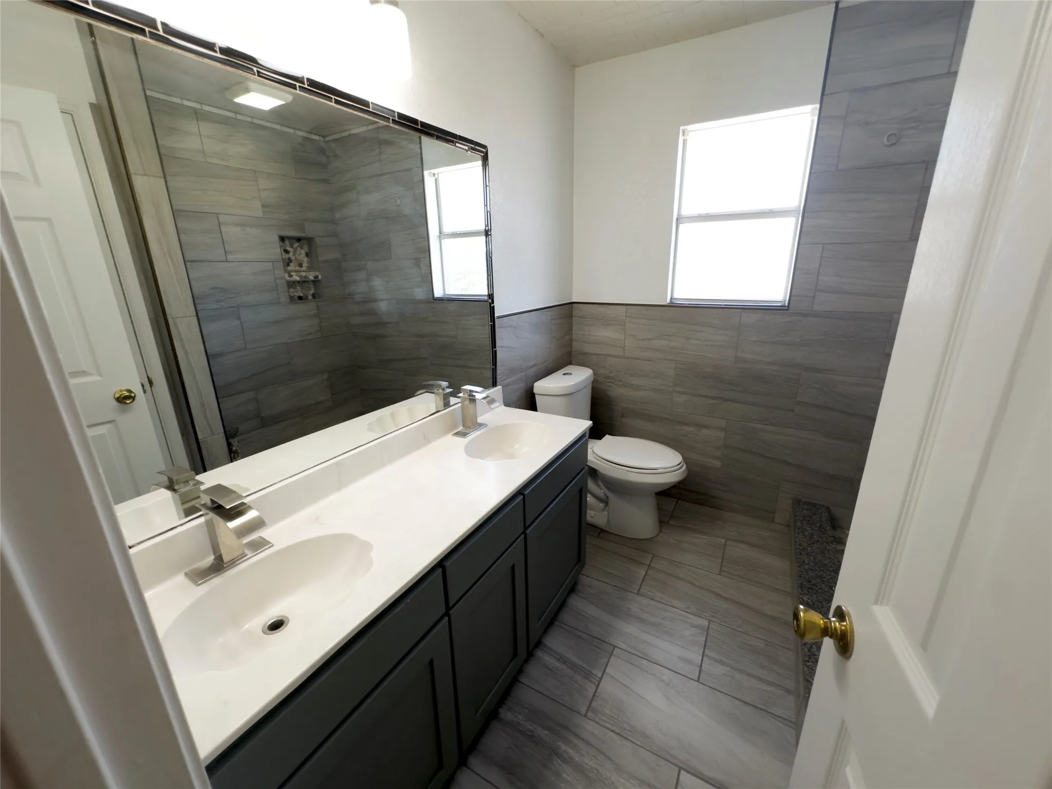 Full bath with tile walls, double vanity, and a tile shower